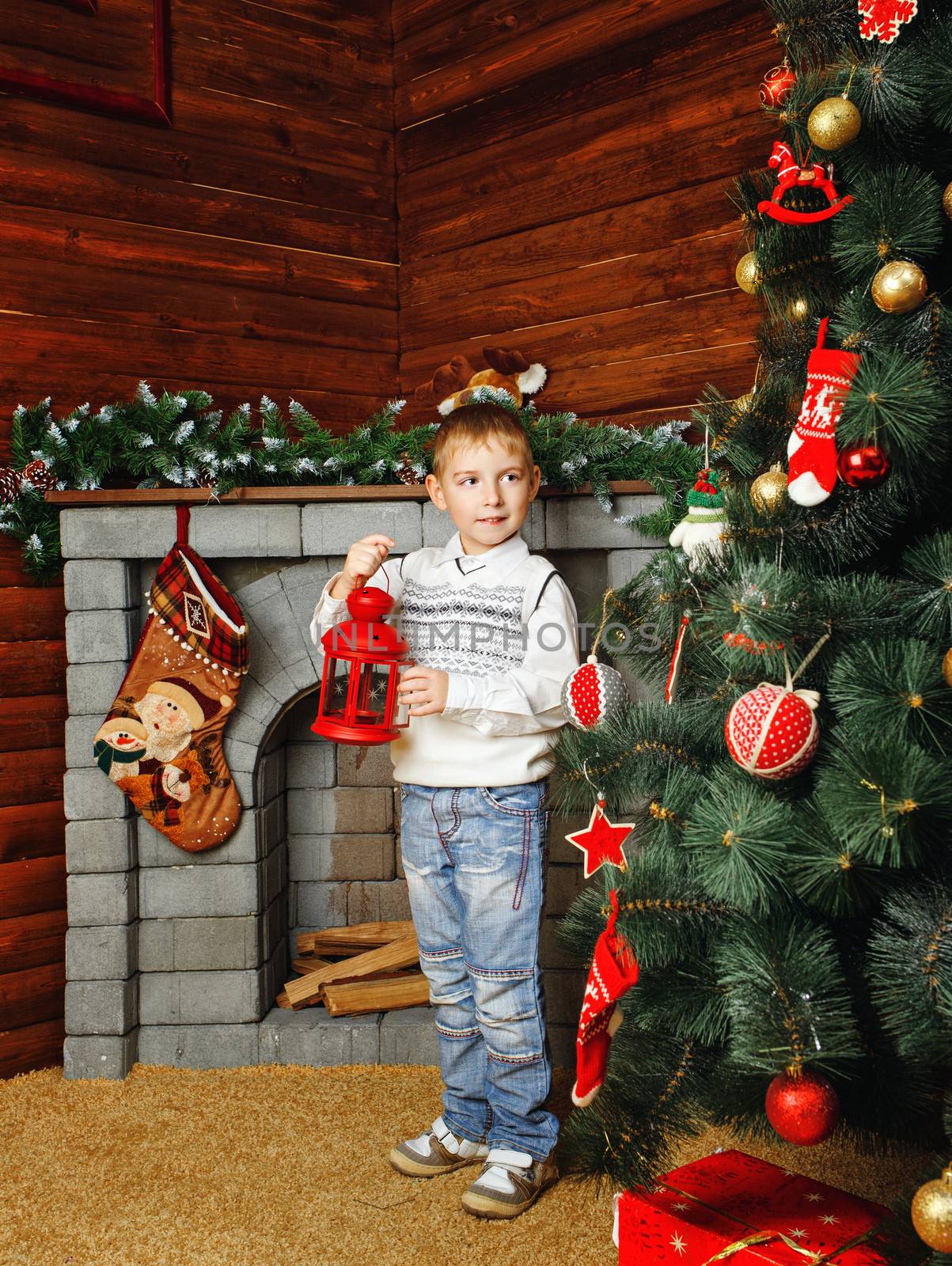 Boy shot on background with Christmas tree, gifts and fireplace