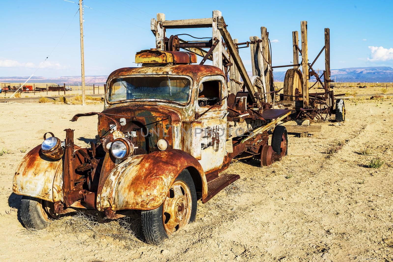 vintage truck abandoned and rusting away in the desert, ghost town in the background 