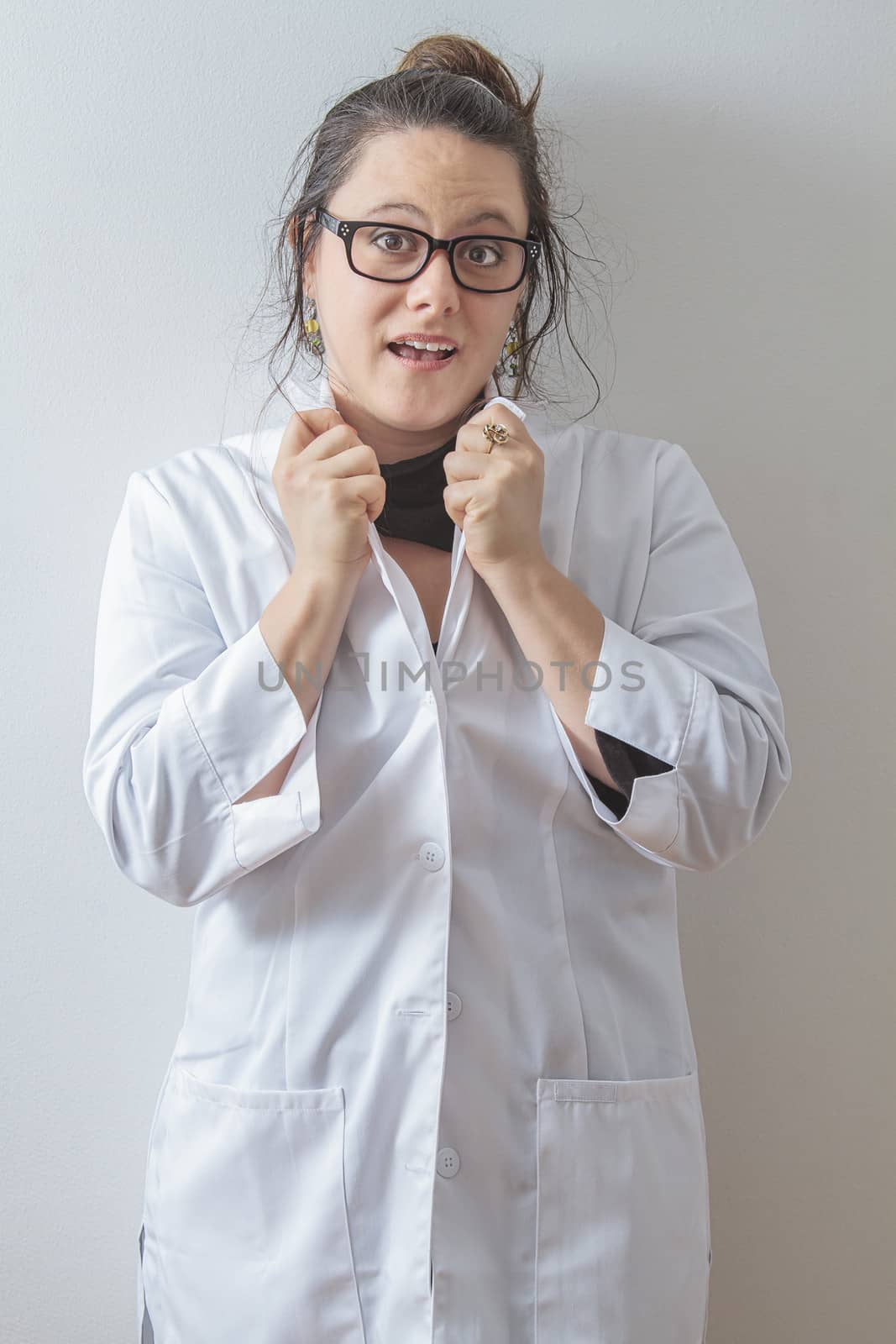 thirtie something brunette woman wearing a lab coat holding up her collar