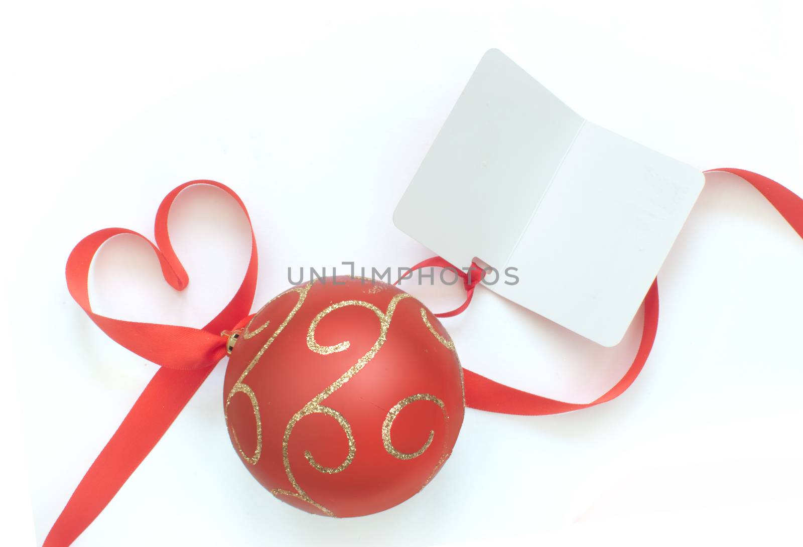 Heart shaped ribbon bow attached to christmas bauble and blank gift tag card 