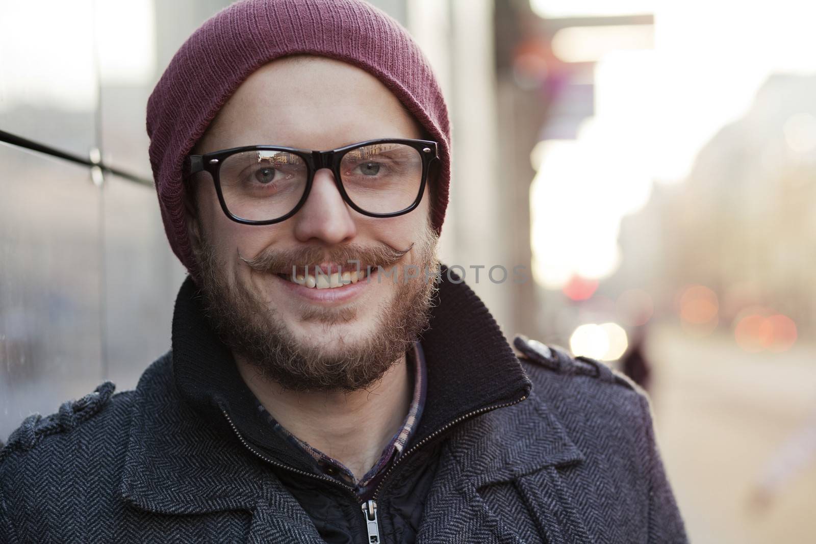 Young smiling hipster with moustache, beard and glasses