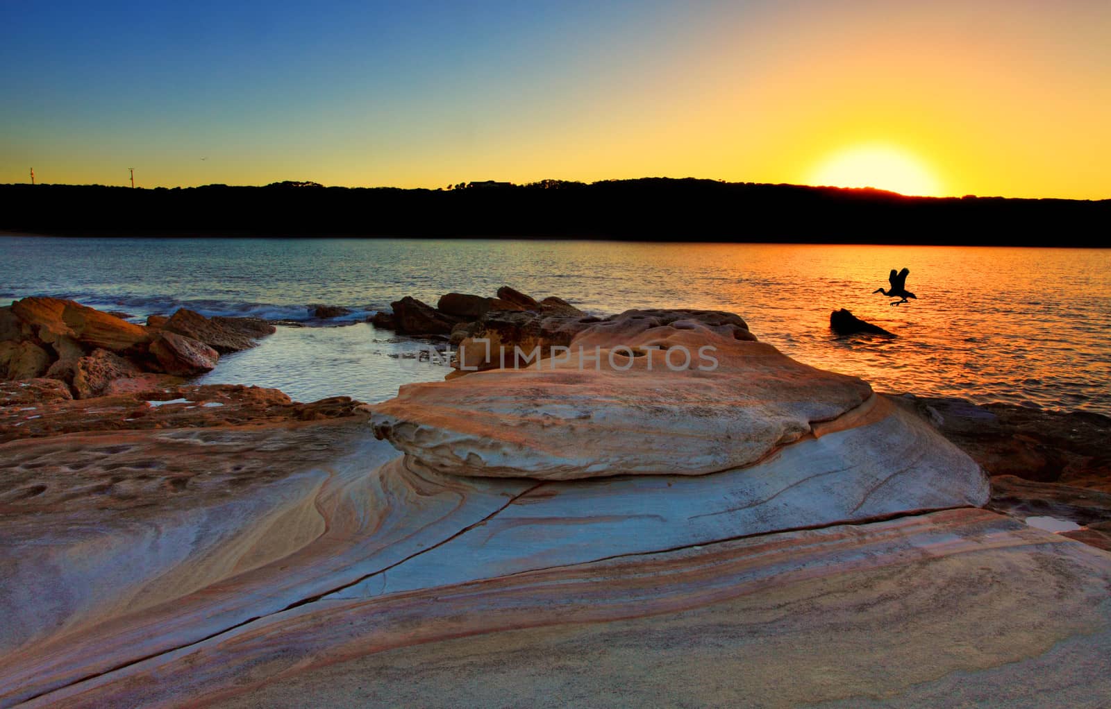 Looking at the sunrise from Bare Island, La Perouse, Sydney Australia. Beautiful sandstone rocks in the foreground.  Bracketed exposure with filter.