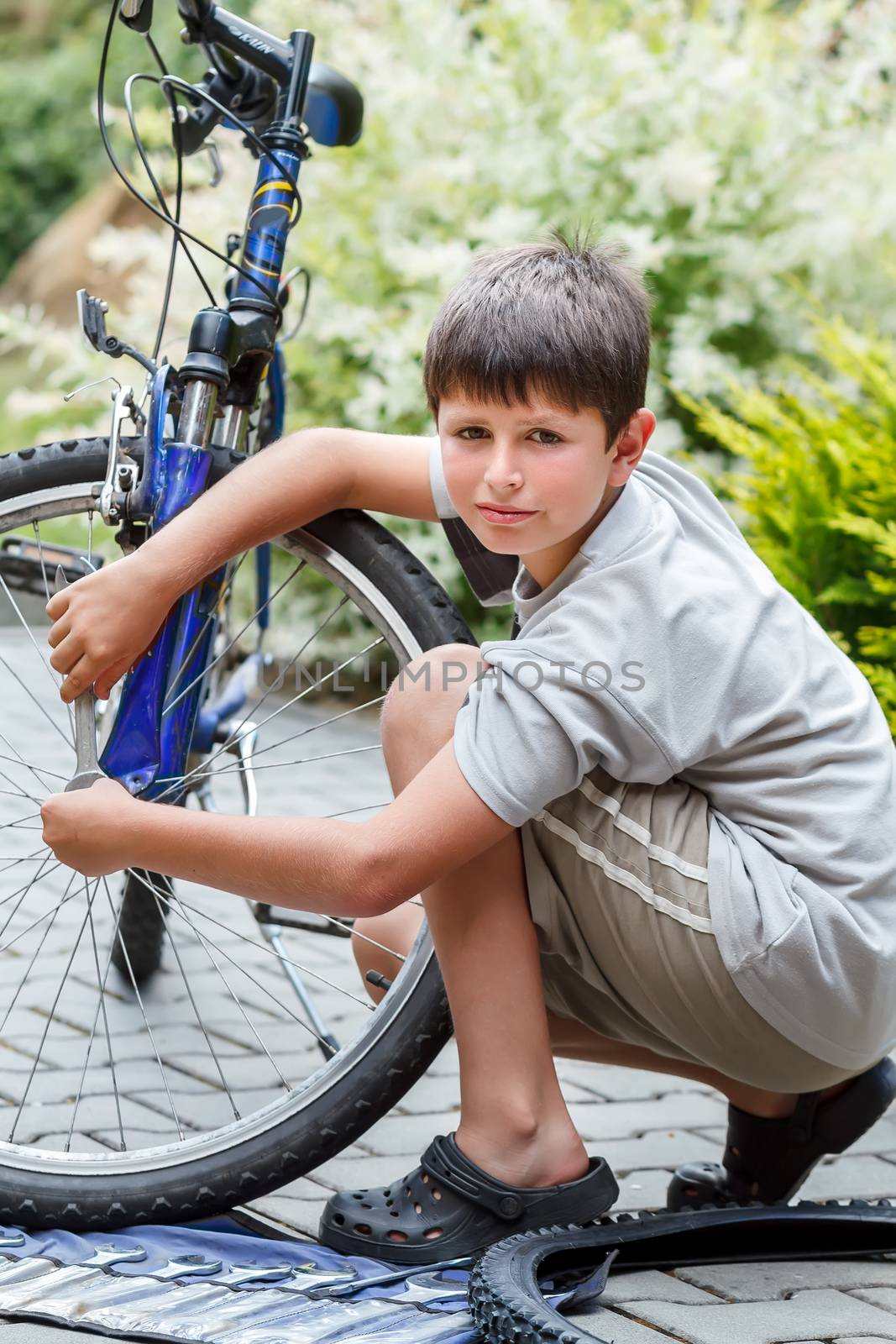 Teenager repairing his bike, using spanner to change broken tyre, outdoor shoot