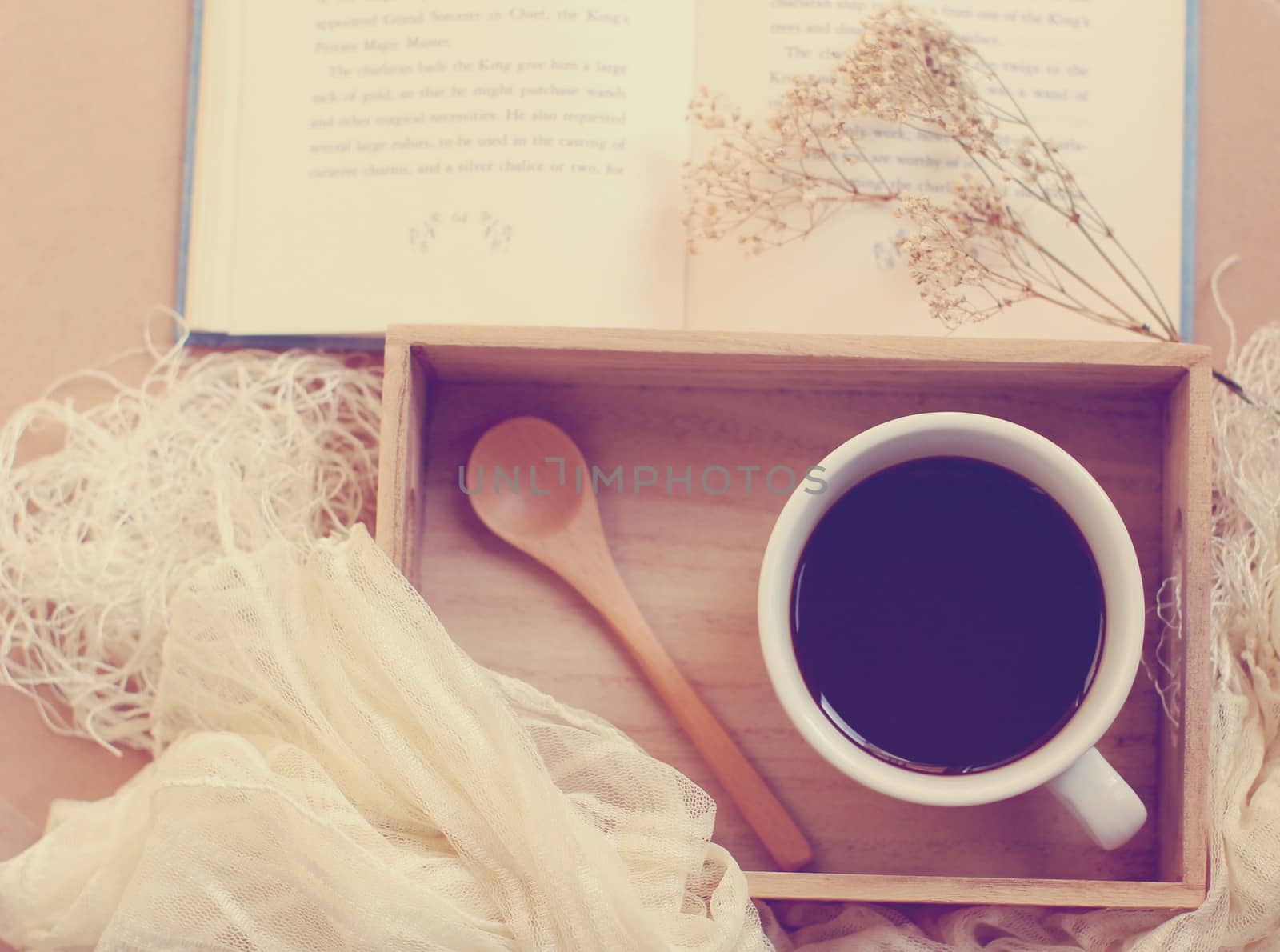 Black coffee and spoon on wooden tray with book, retro filter effect