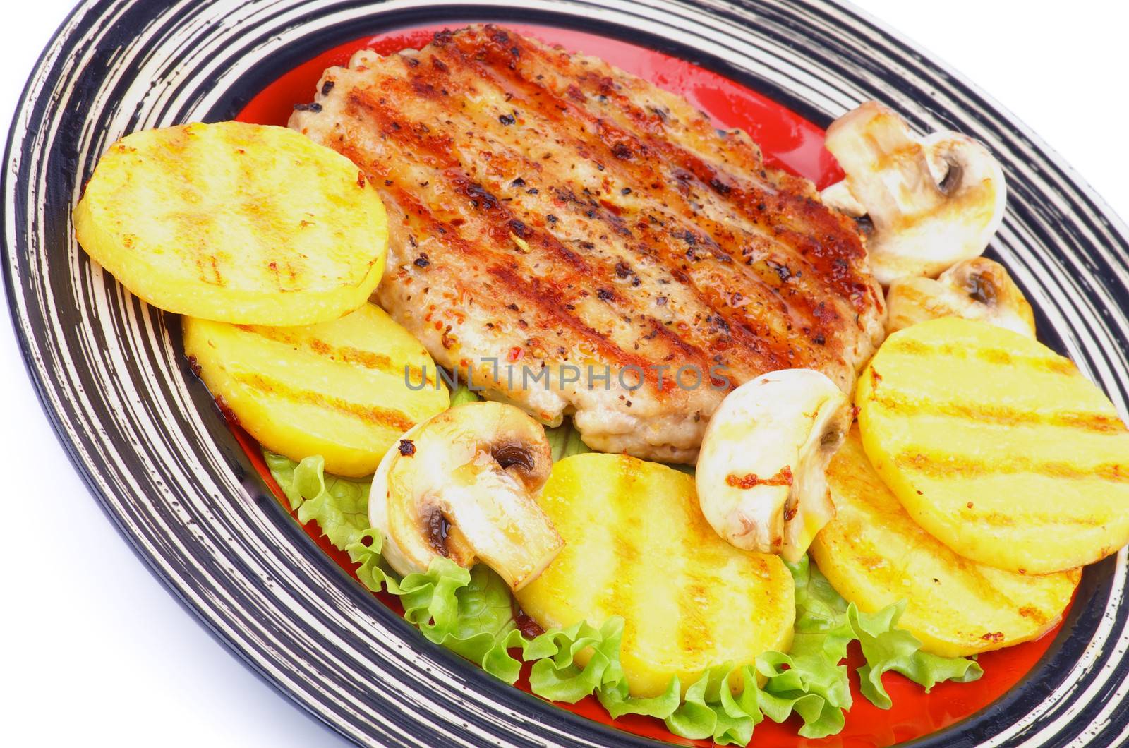 Roasted Turkey Steak Garnished with Grilled Sliced Potato, Portabello Mushrooms and Lettuce closeup on Striped Plate