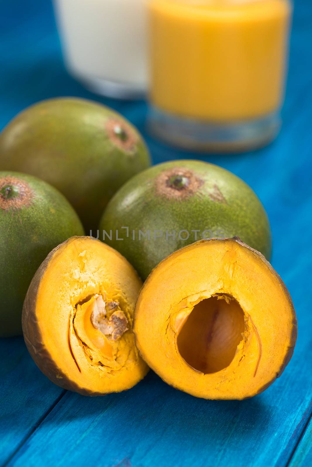 Peruvian fruit called Lucuma (lat. Pouteria lucuma) which has a dry, sweet flesh, and is mostly used to prepare juices, milkshakes, yogurts, ice cream and other desserts (Selective Focus, Focus on the upper right part of the right lucuma half) 