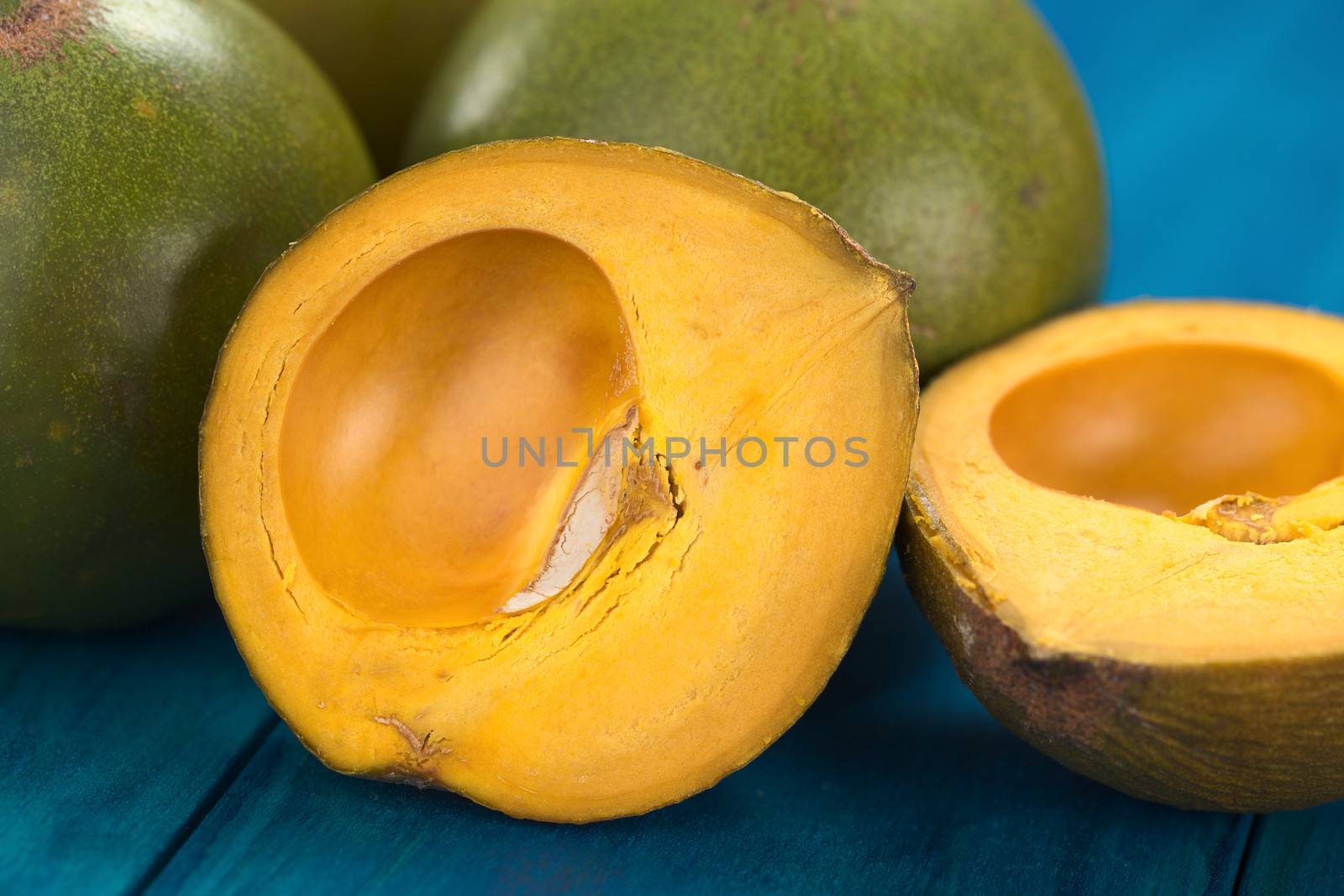 Peruvian fruit called Lucuma (lat. Pouteria lucuma) which has a dry, sweet flesh, and is mostly used to prepare juices, milkshakes, yogurts, ice cream and other desserts (Selective Focus, Focus on the standing lucuma half) 