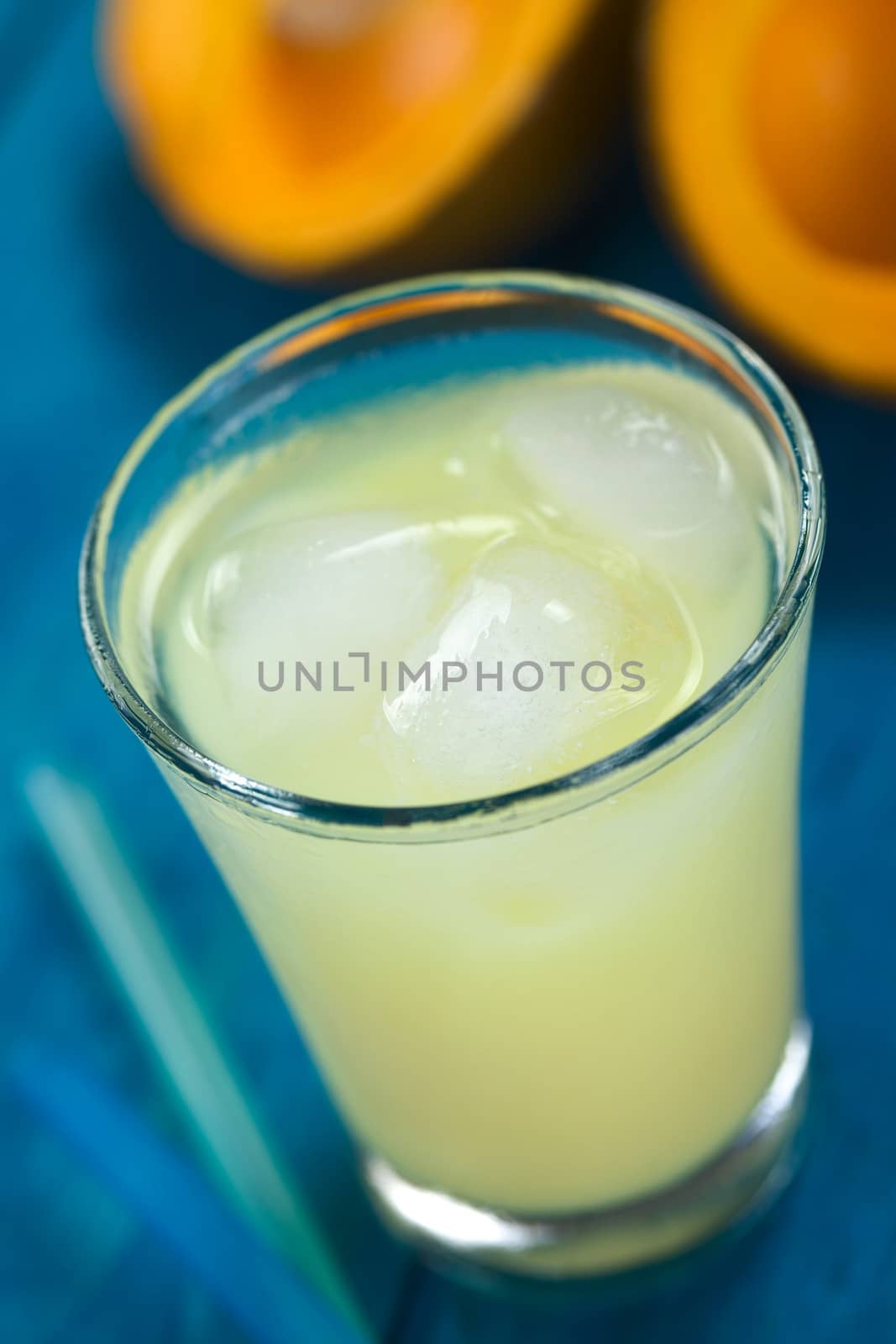 Peruvian cream liqueur made of lucuma fruit served in glass with ice cubes (Selective Focus, Focus on the front of the first ice cube)