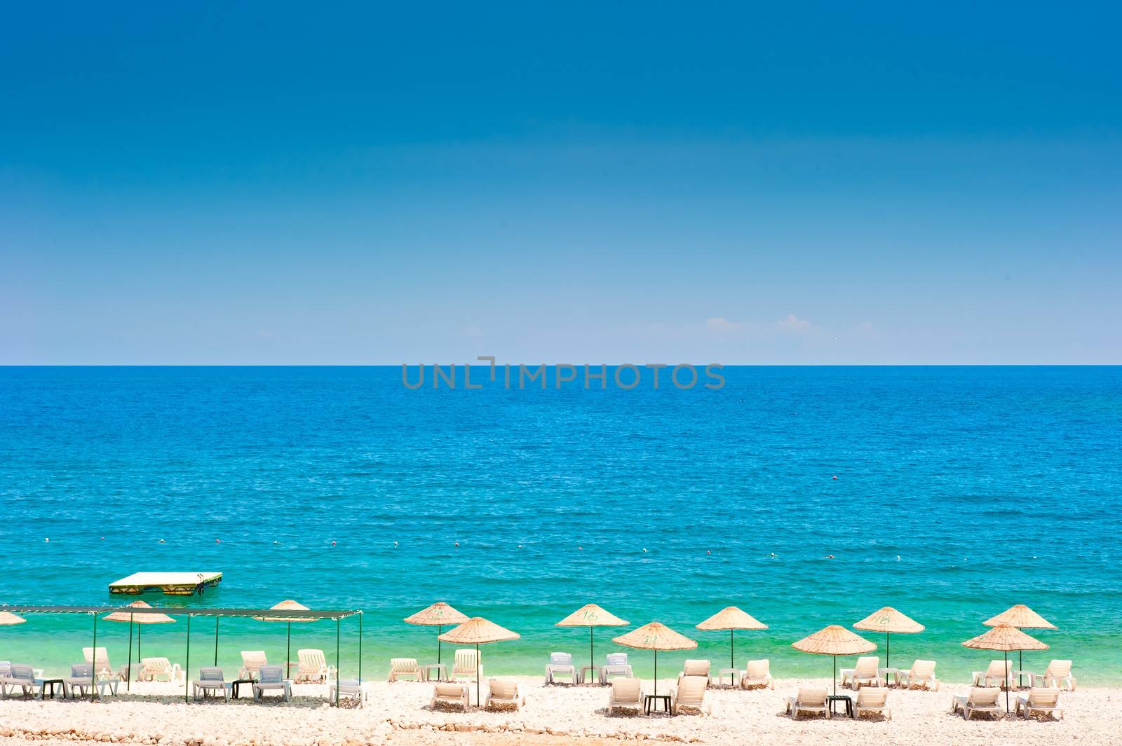 empty beach with white wicker umbrellas