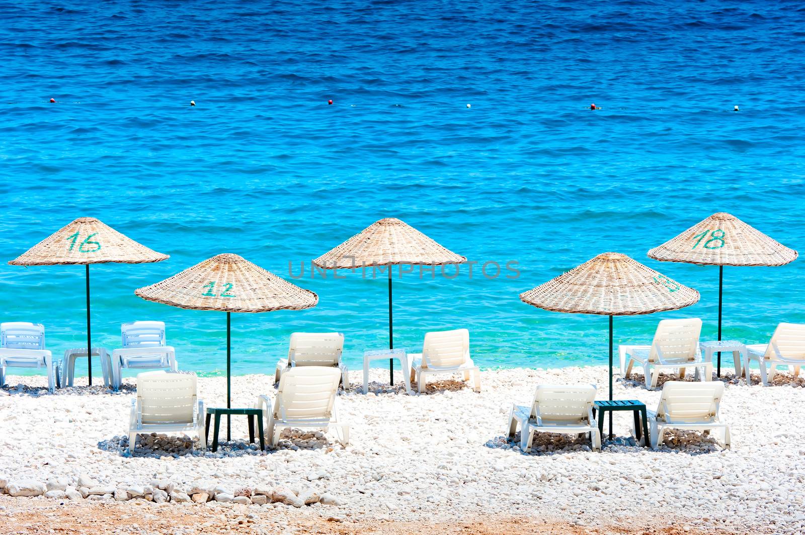 free deck chairs by the sea and thatched umbrellas