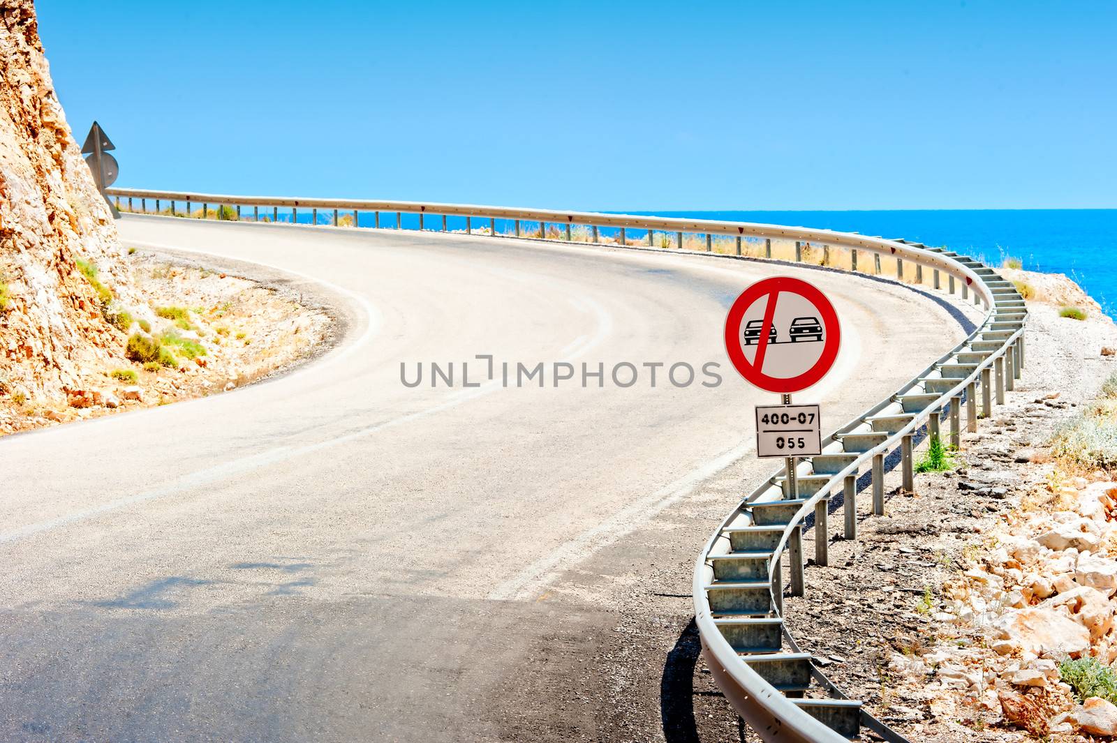 road sign and a mountain road along the sea