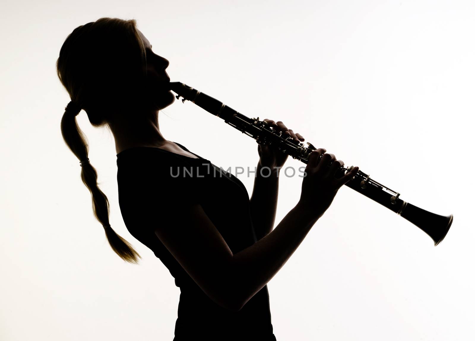 Female Musician Practices her Woodwind Technique on a Clarinet Photographed in silhouette