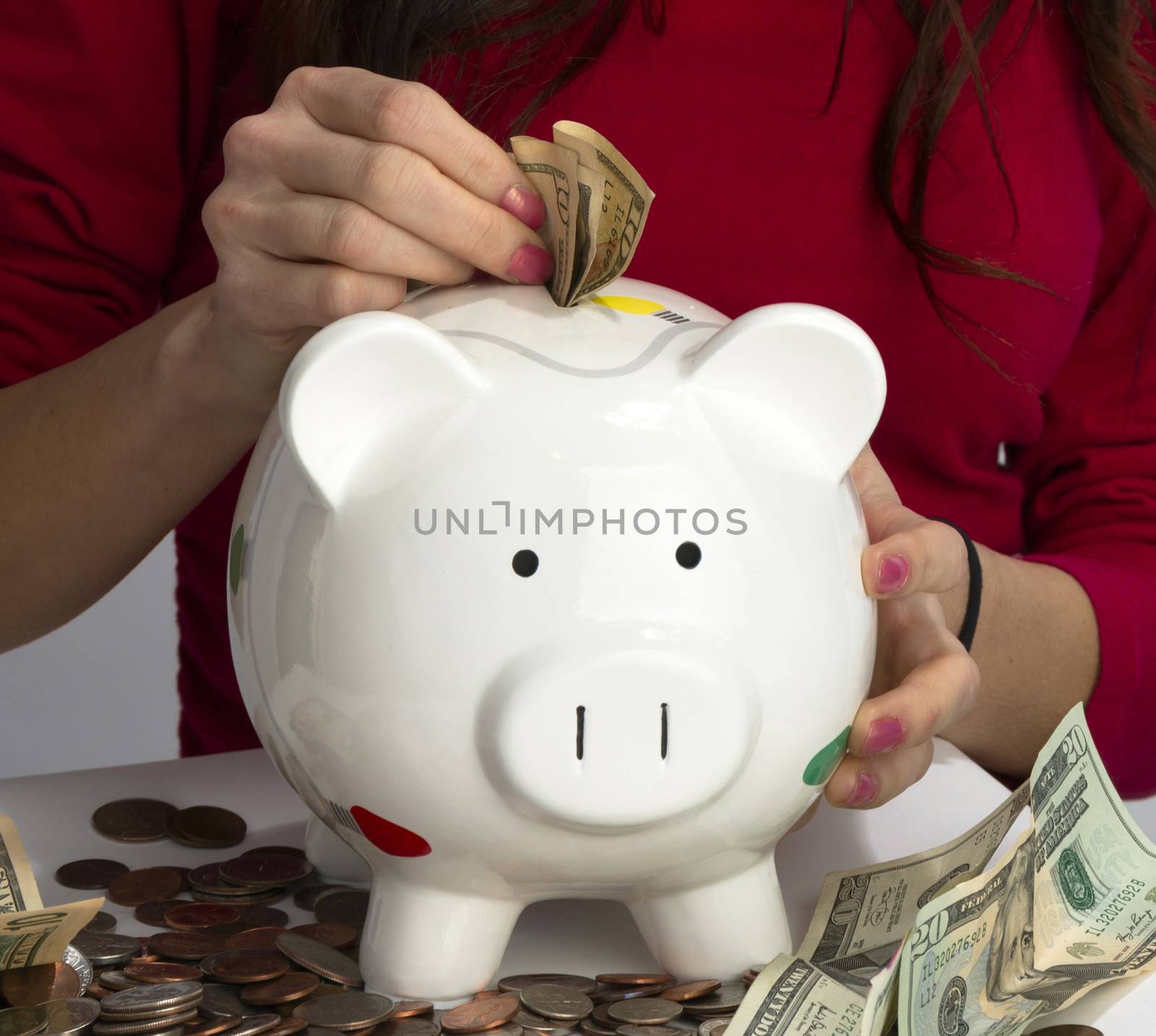 Female hand fills Piggy Bank with American Cash Currency