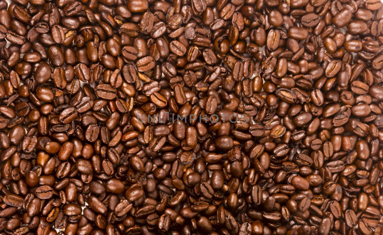 a flat pile group of roasted dark brown coffee beans