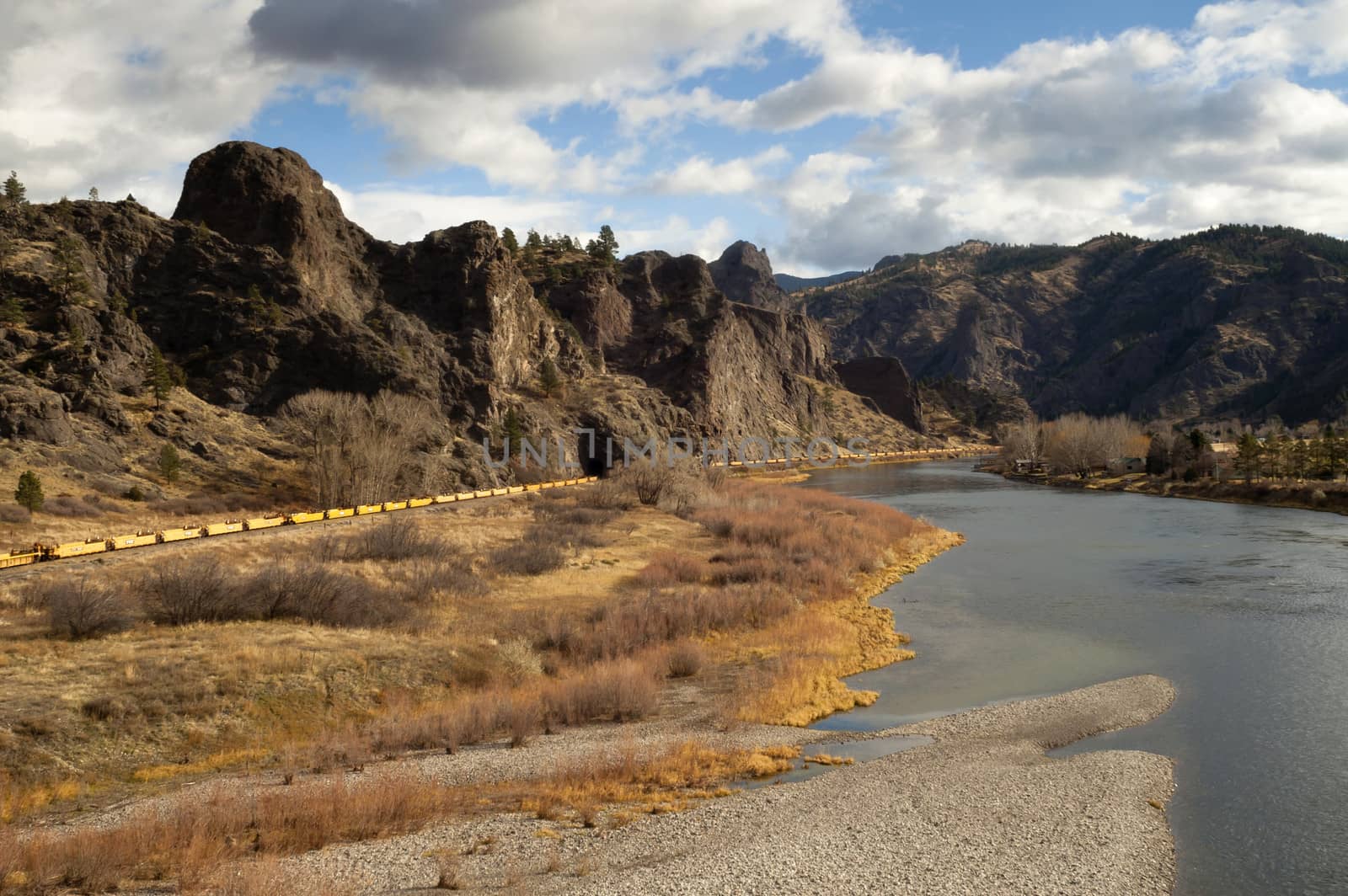 Yellow railcars sits in a low river bend in the Rocky Mountains