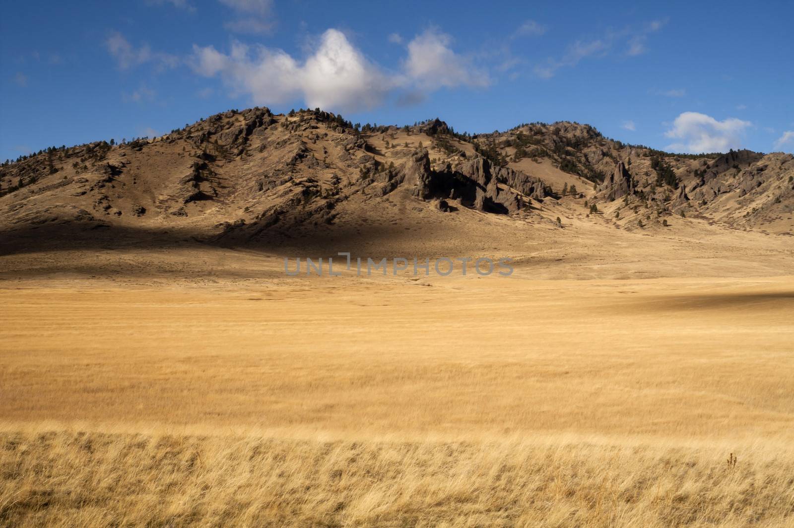 Grassland leads up to rocky hillside in this northern rural landscape