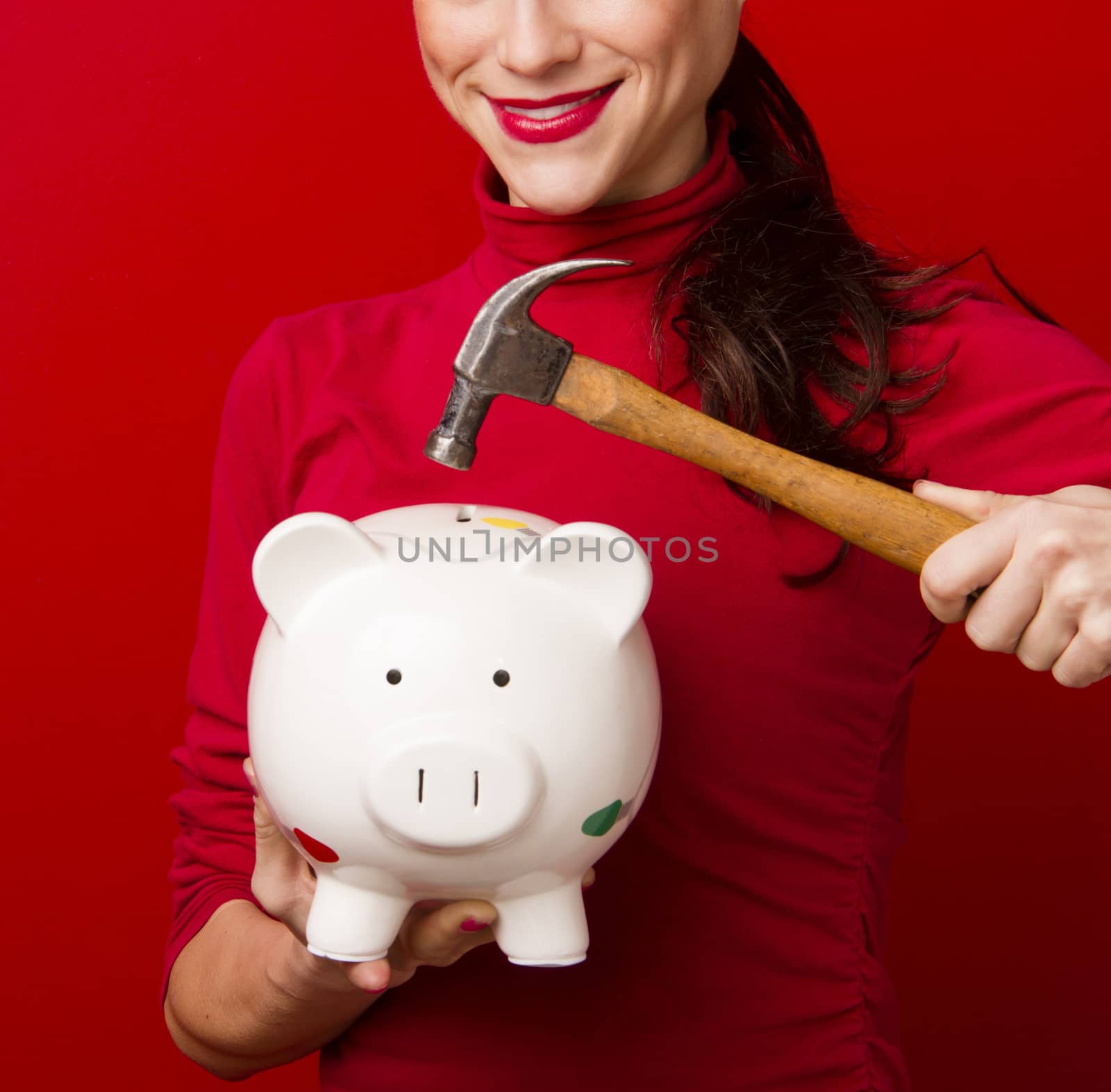 Smiling Woman in Red Holds Hammer Above Piggy Bank Savings by ChrisBoswell