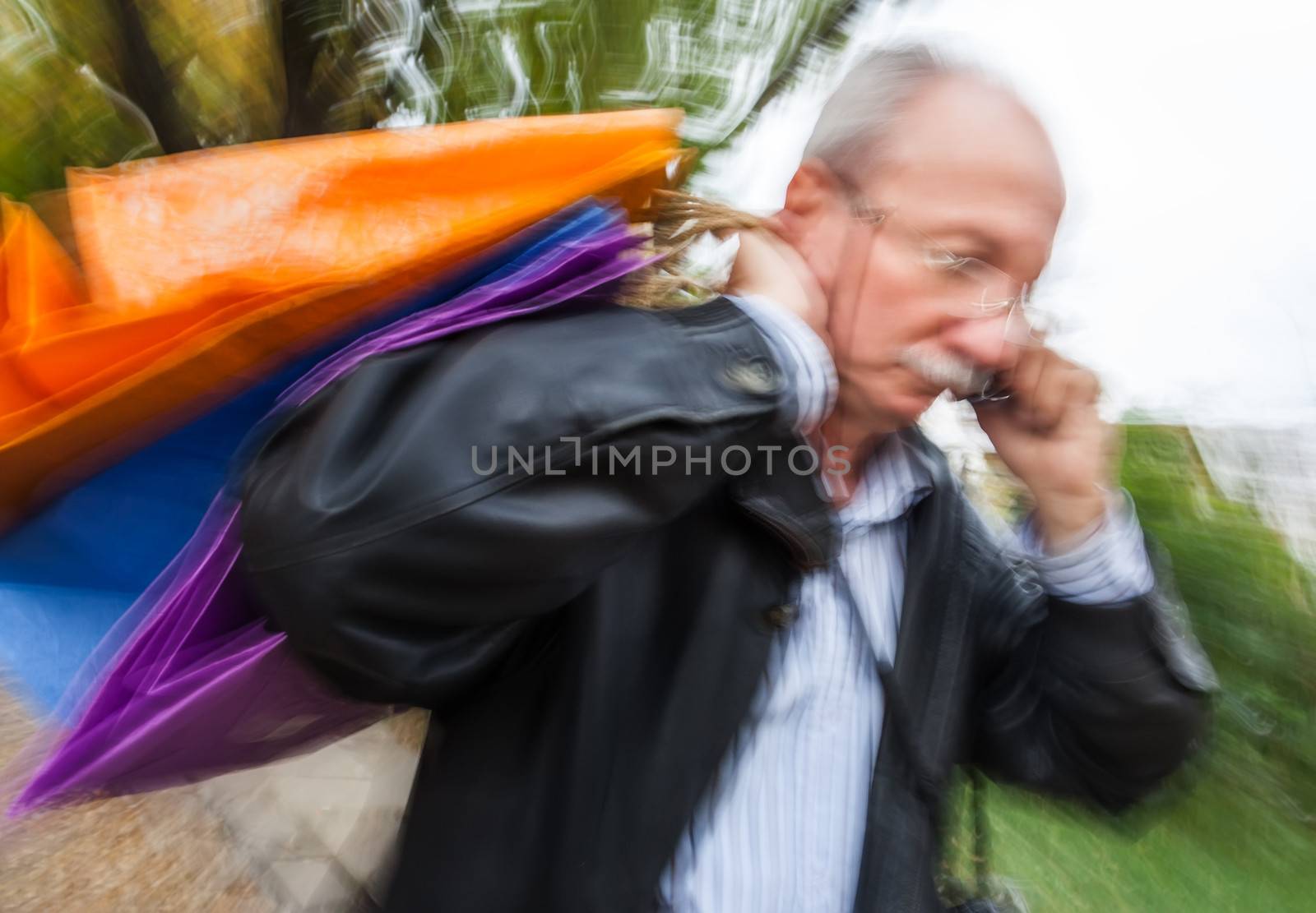 Holiday sales. Man with many shopping bags in his hand talking on a cell phone. Intentional motion blur