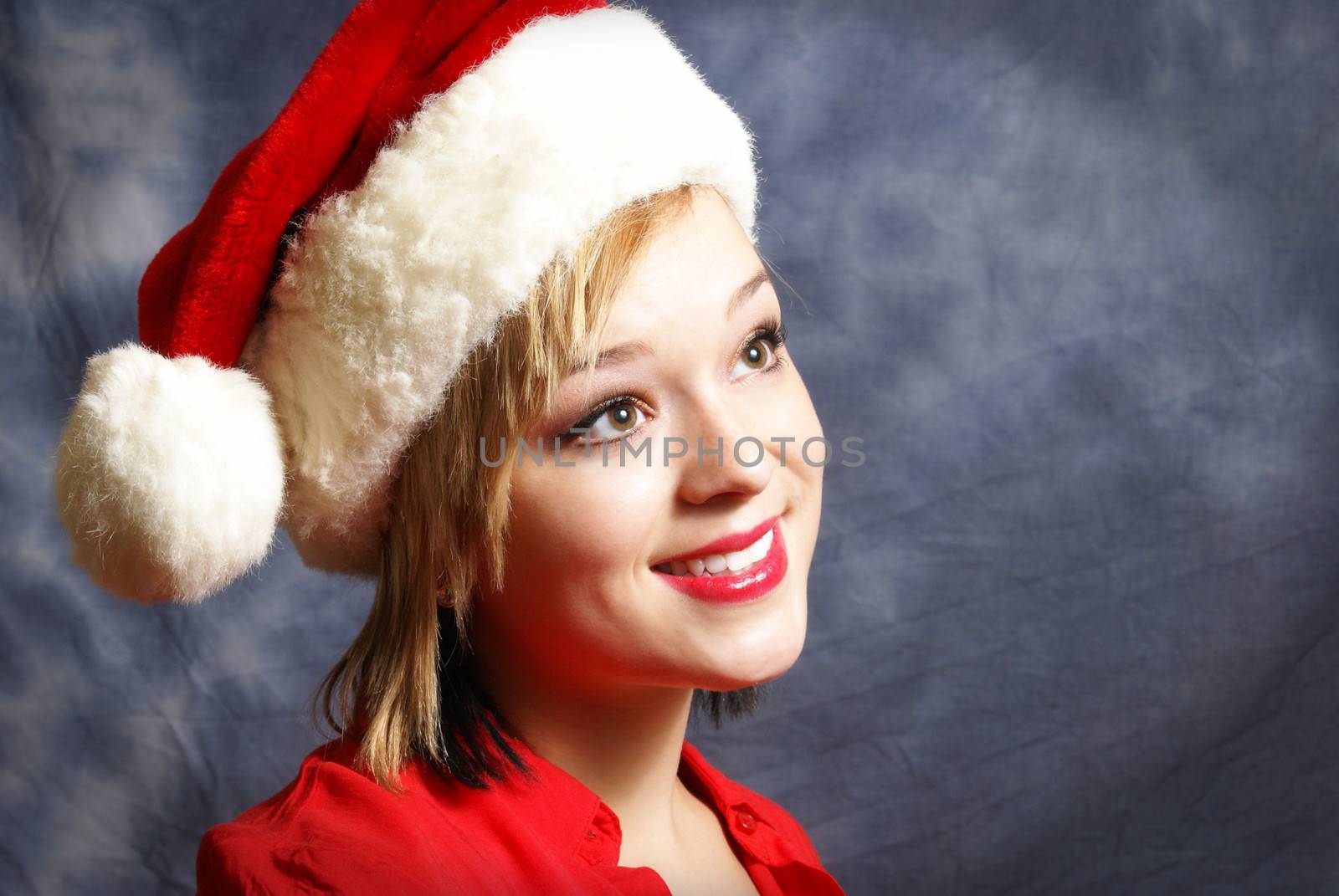 A happy young woman wearing a santa hat for the spirit of Christmas.