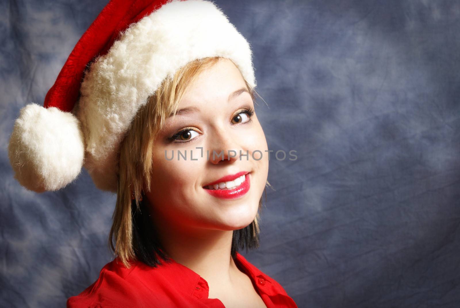 A happy young woman wearing a santa hat for the spirit of Christmas.