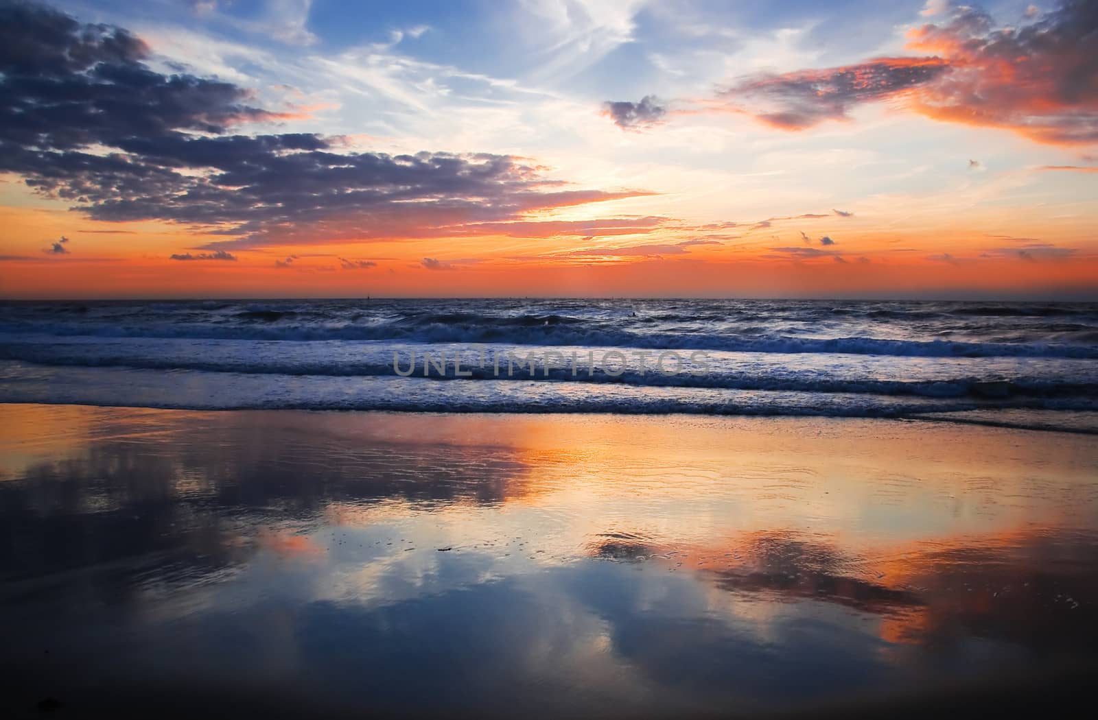 Colorful cloudy sunset at the beach with reflection - horizontal