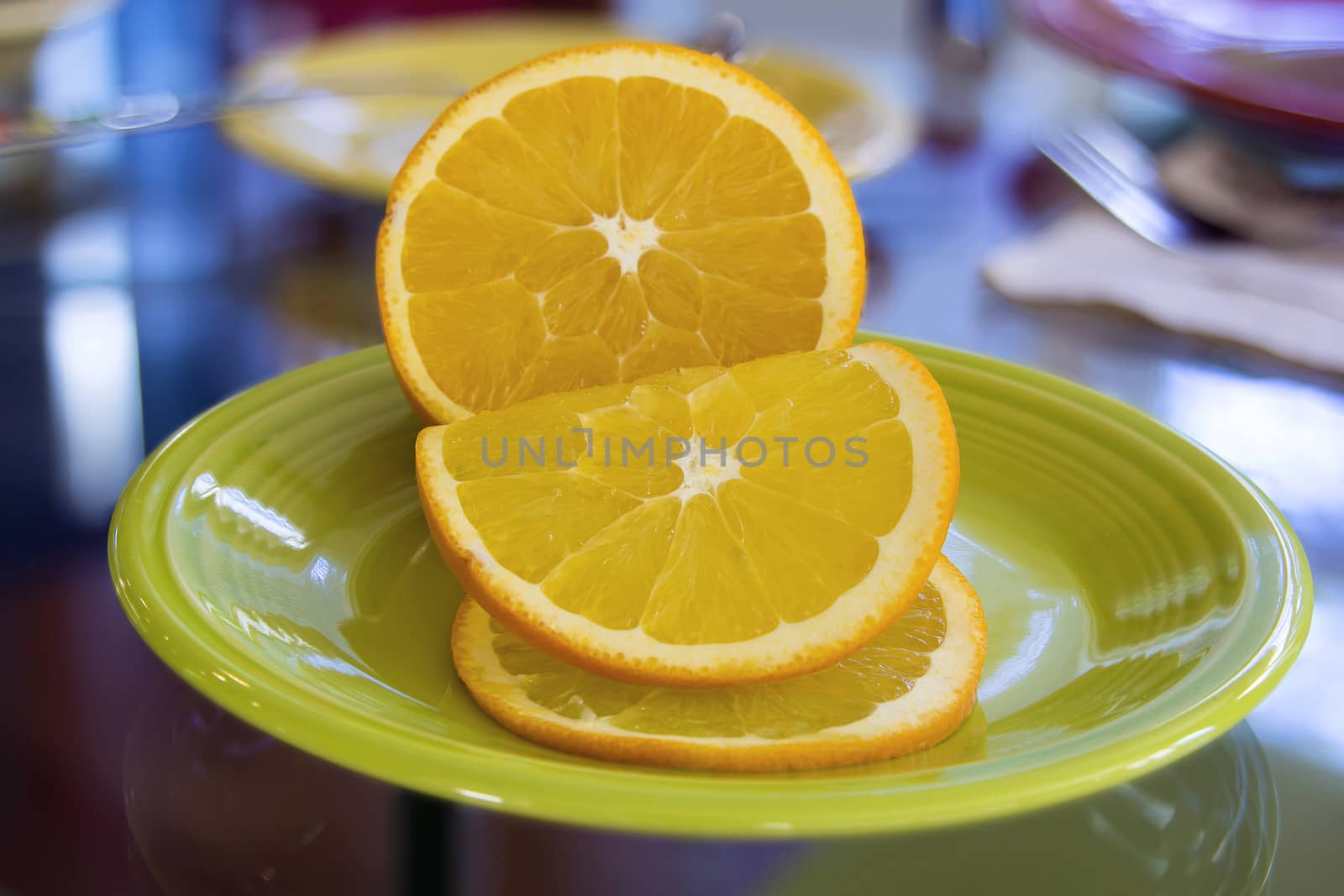 Sliced Orange Fruit for Garnish on Green Plate with Blurred Background Dinner Table Setting