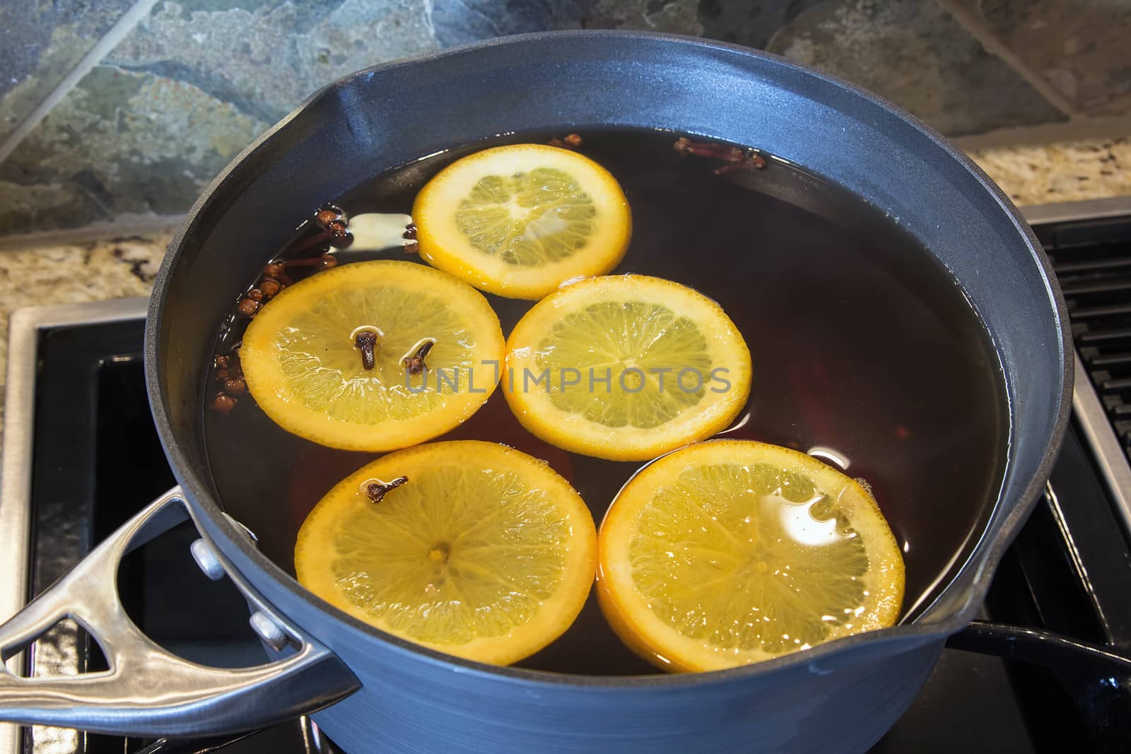 Hot Apple Cider with Orange Slices and Cloves Cooking in Kitchen Pot