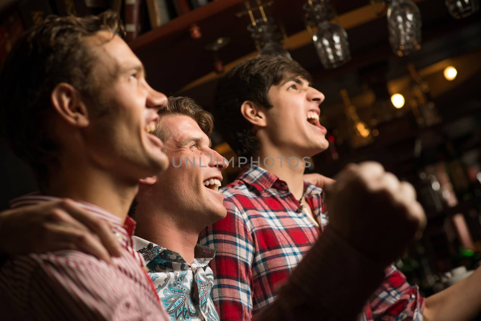 Three men stand in a row embracing smile and look in front of you, sports fans