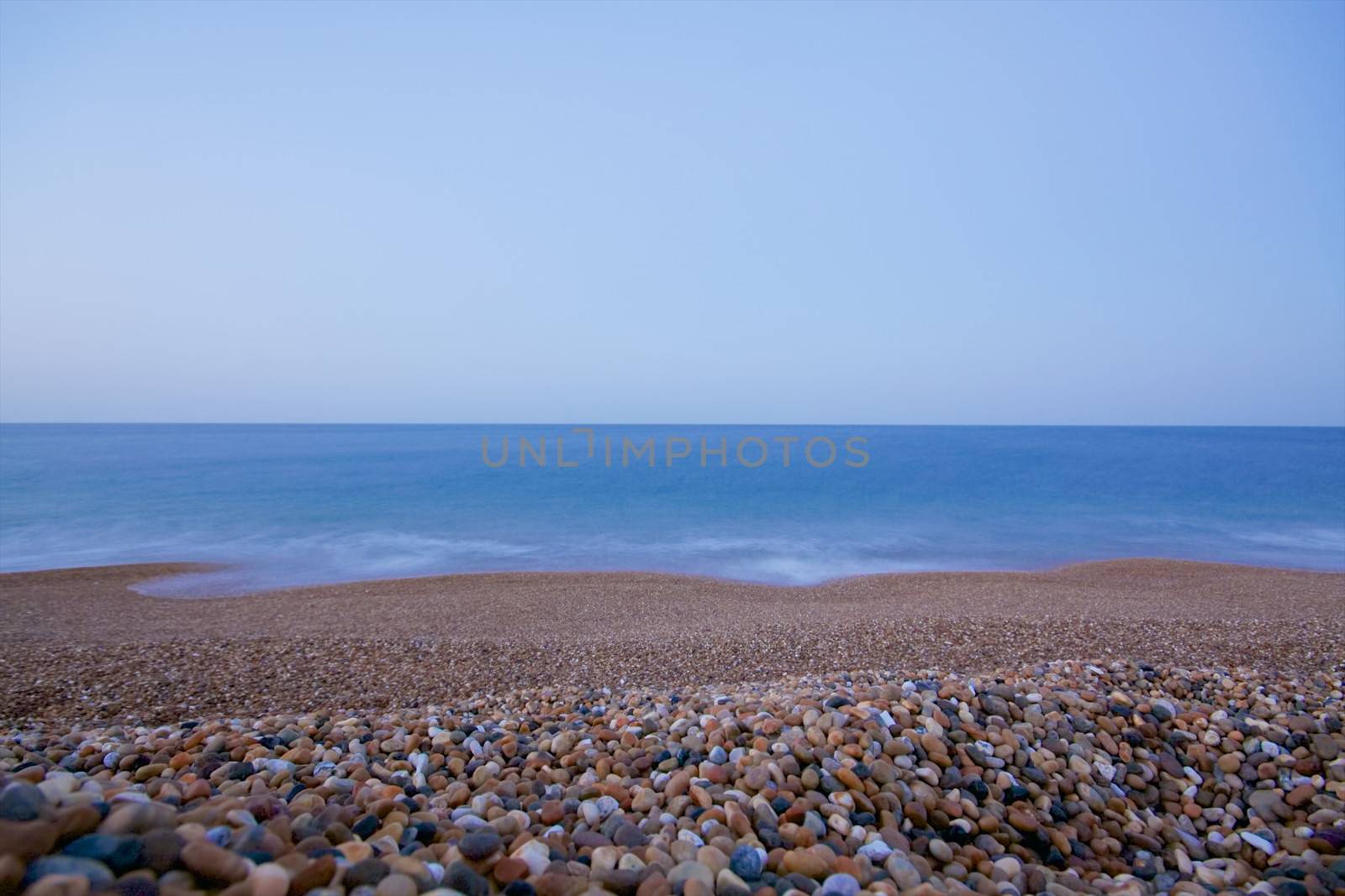 Pebble beach with calm blue ocean, long exposure