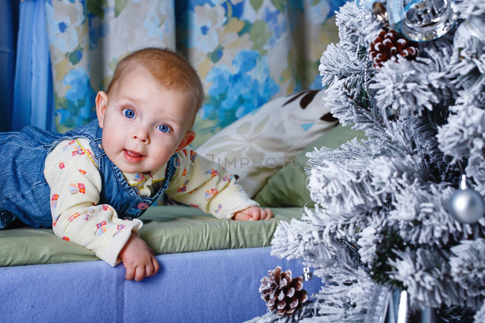 Redhead babe with blue eyes lies near Christmas tree