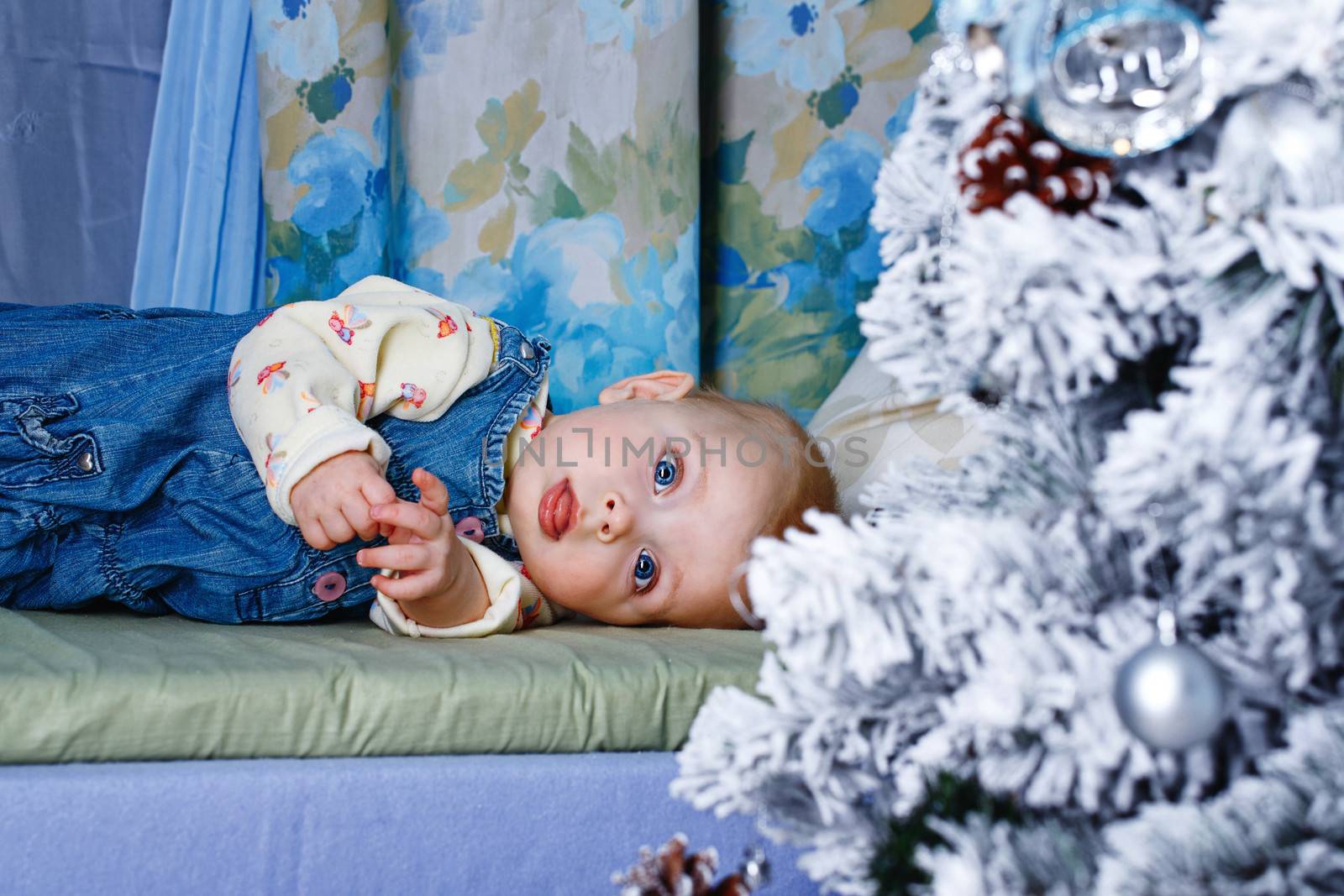 Redhead babe with blue eyes lies near Christmas tree