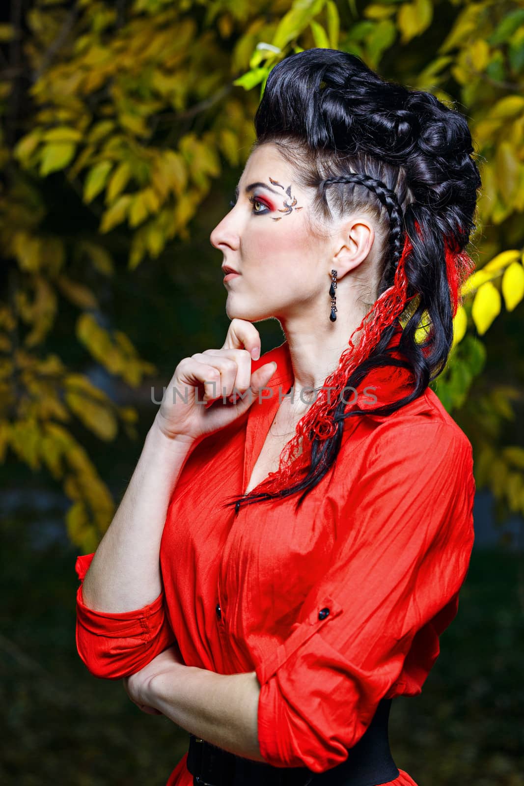 Young attractive girl in red shirt and with makeup close-up portrait in autumn park