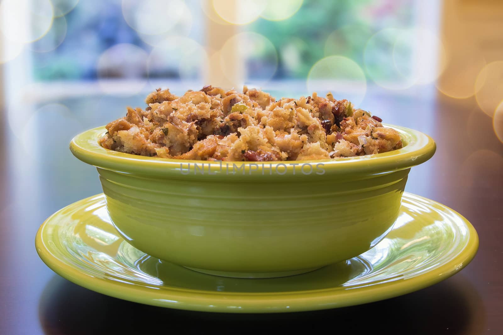 Thanksgiving Day Turkey Stuffing with Corn Bread Celery Cranberry in Green Bowl on Wood Table with Blurred Bokeh Lights