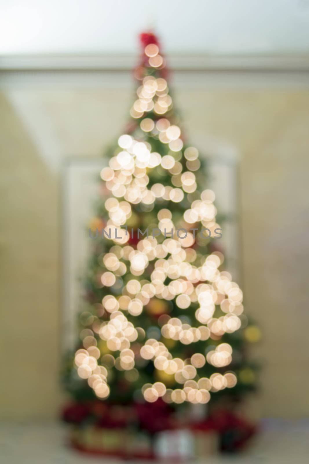 Christmas Tree Defocused Decoration Ornaments Ribbons Poinsettia and Presents Under the Tree with Bokeh Lights 