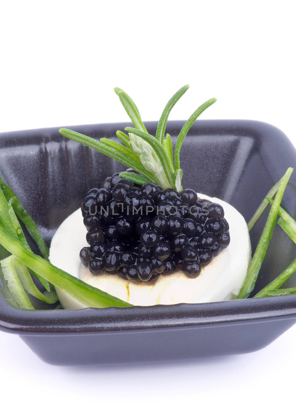 Delicious Snack with Black Caviar, Boiled Eggs, Rosemary and Sliced Cucumber in Black Plate closeup on white background