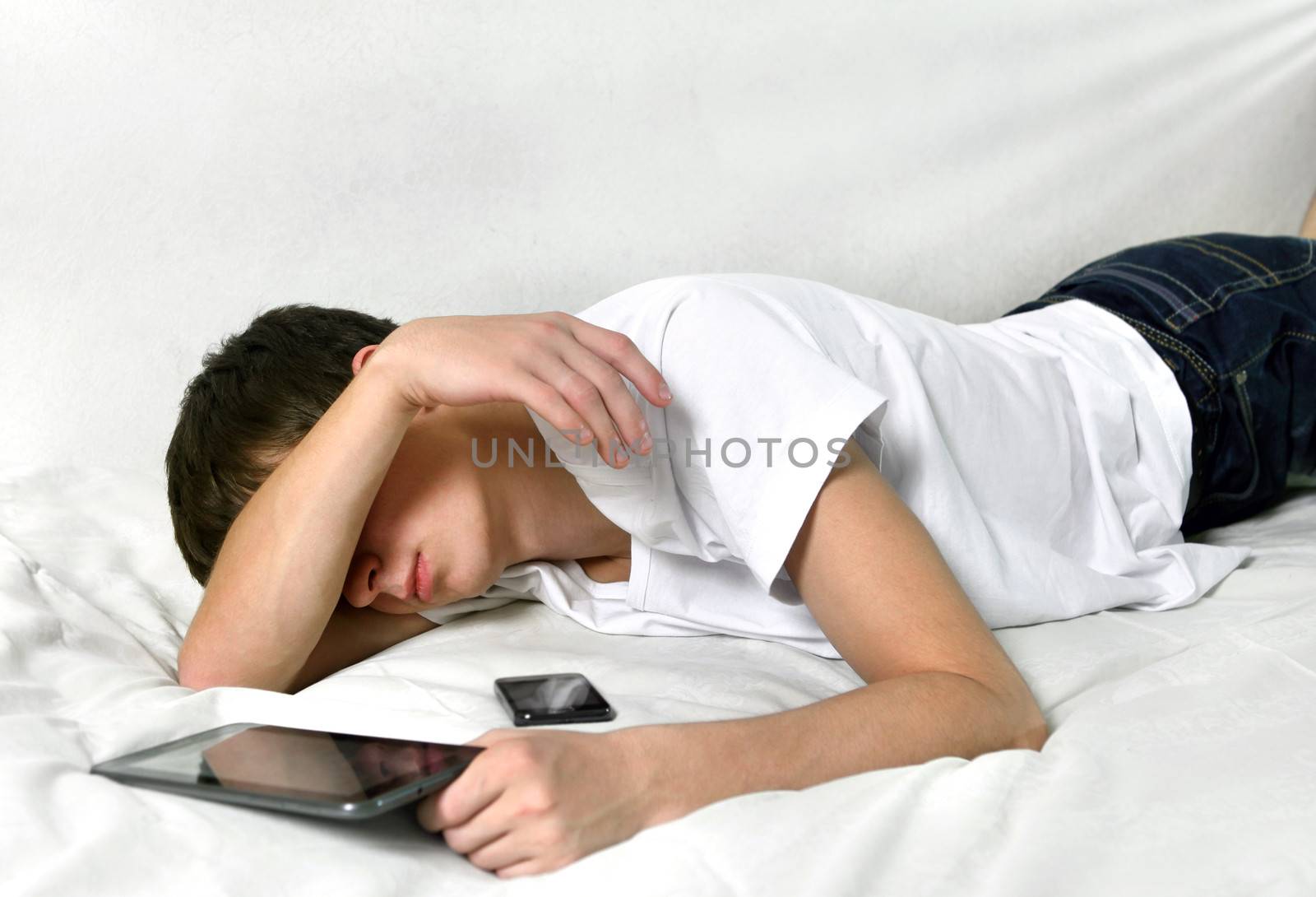 Tired Young Man Sleeps with Tablet Computer on the bed