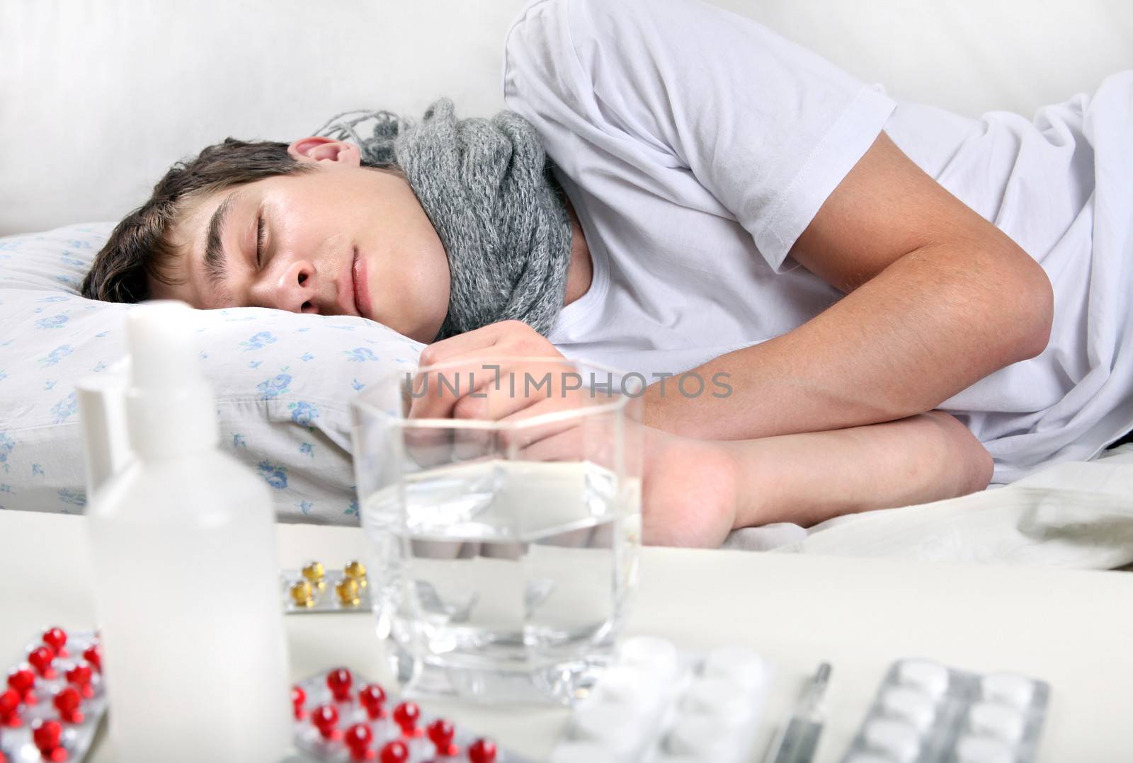 Sick Young Man sleeping on the Bed near the table with a pills