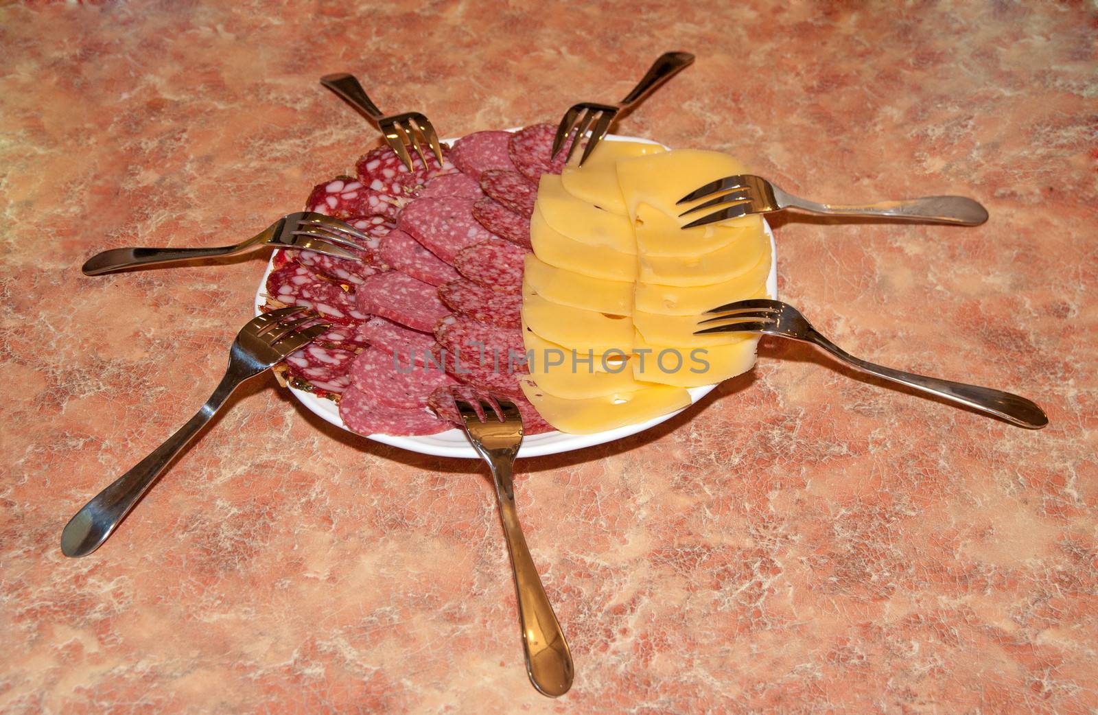 Plate with cheese and sausage in an environment of forks.