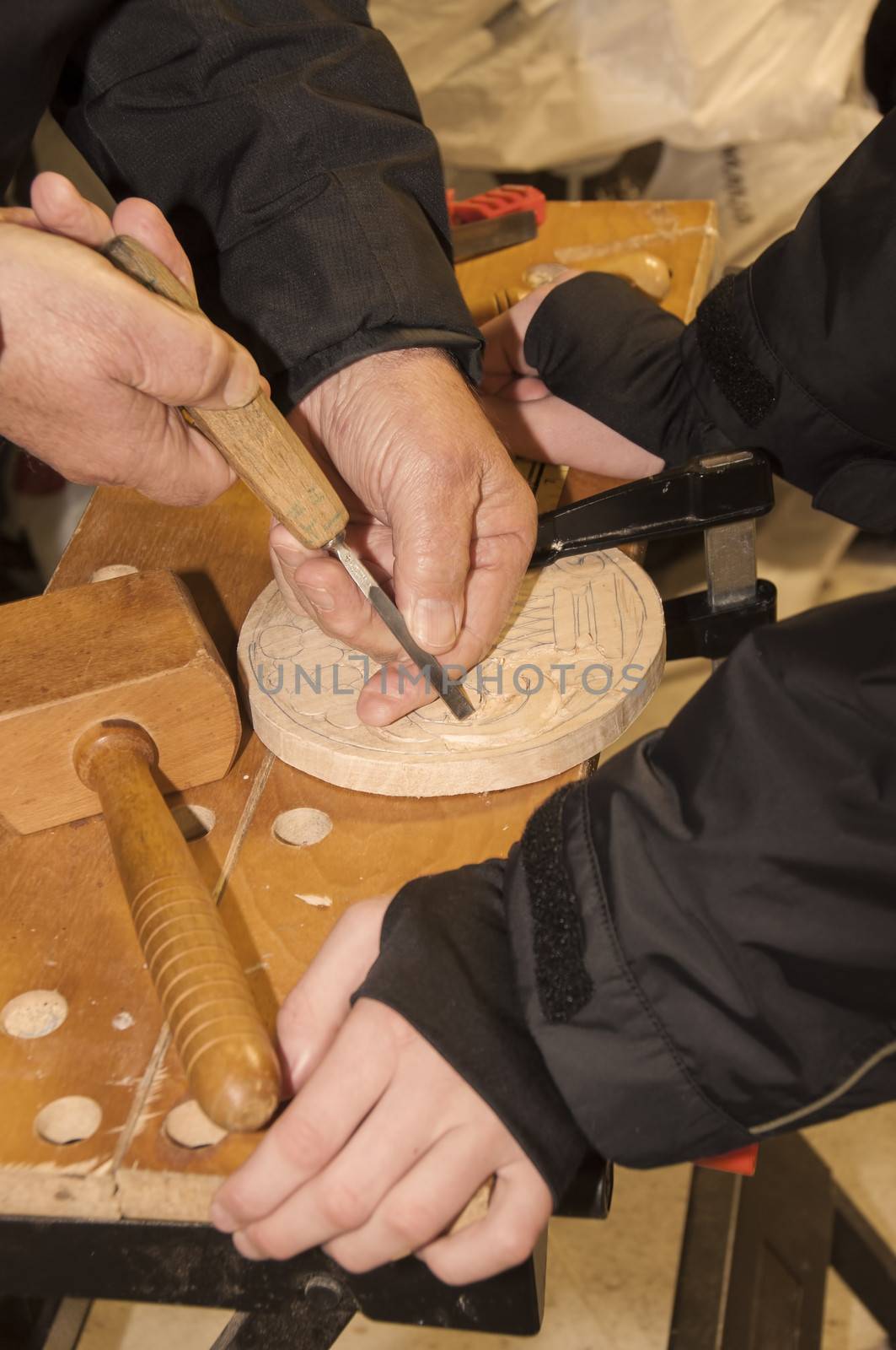A grandfather is teaching his grandson woodcarving