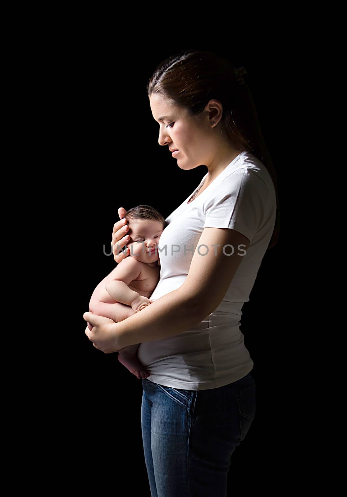 Beautiful mother holding a newborn in her belly on black background