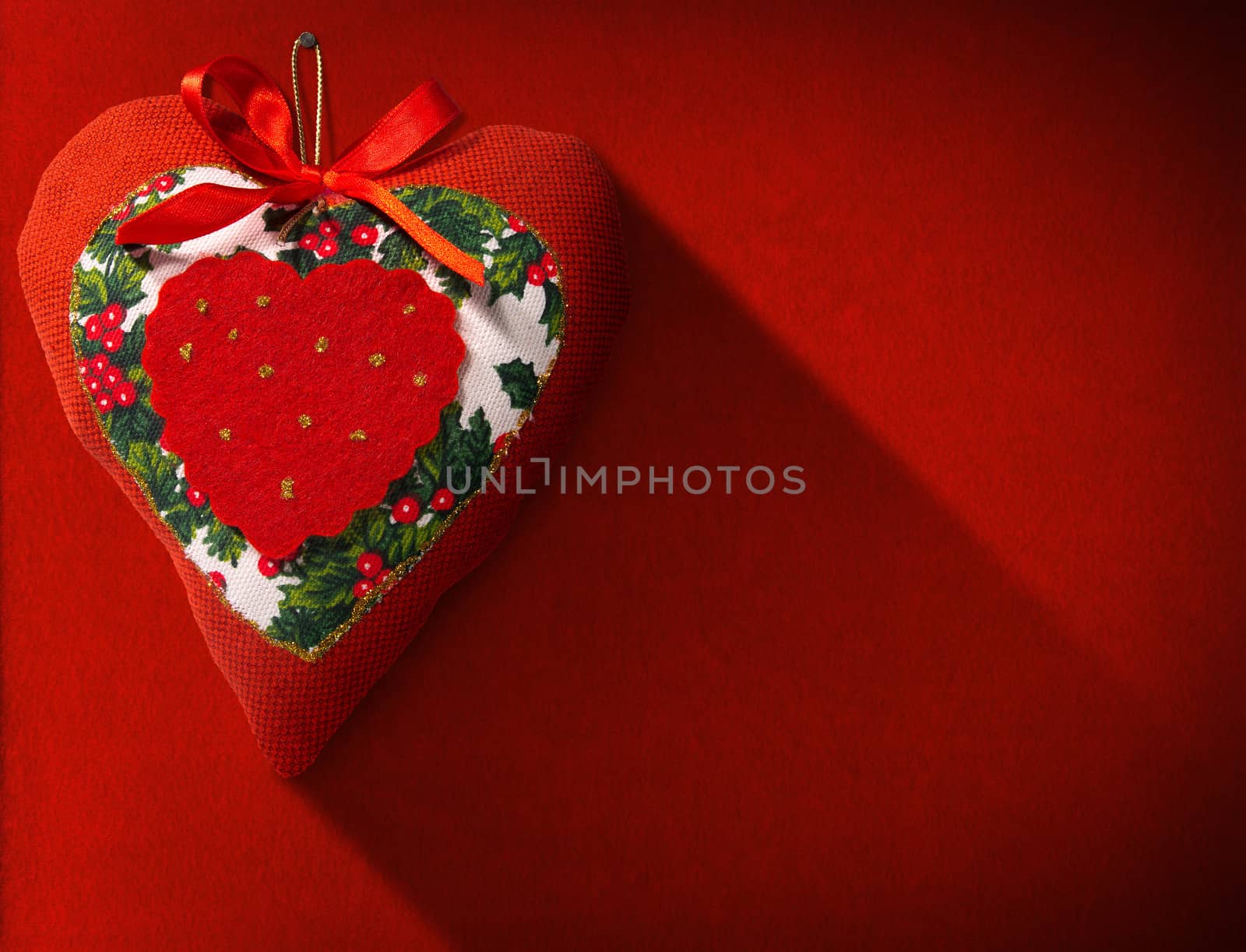 Christmas heart, red, white and green hanging on red velvet background with shadows