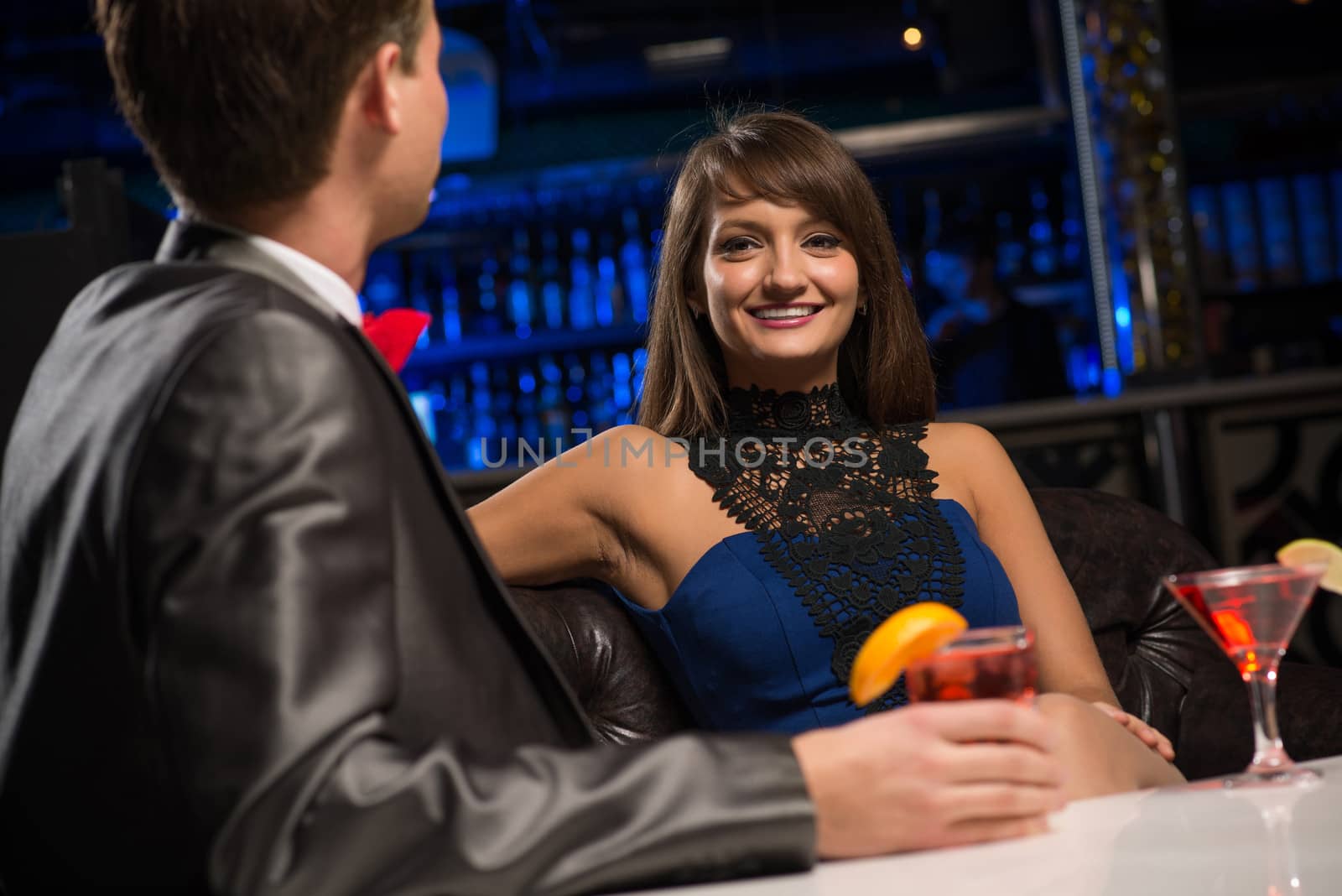 portrait of a woman in a nightclub, sitting on the couch and talking with man