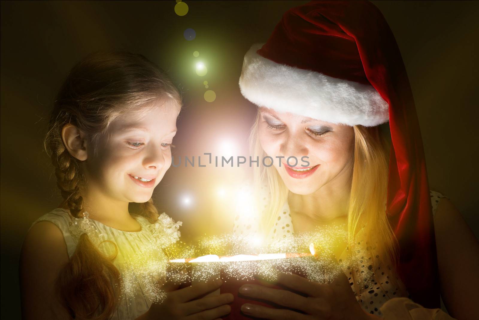 mother in Santa Claus cap and daughter opened a box with Christmas gift boxes of shining light and magic