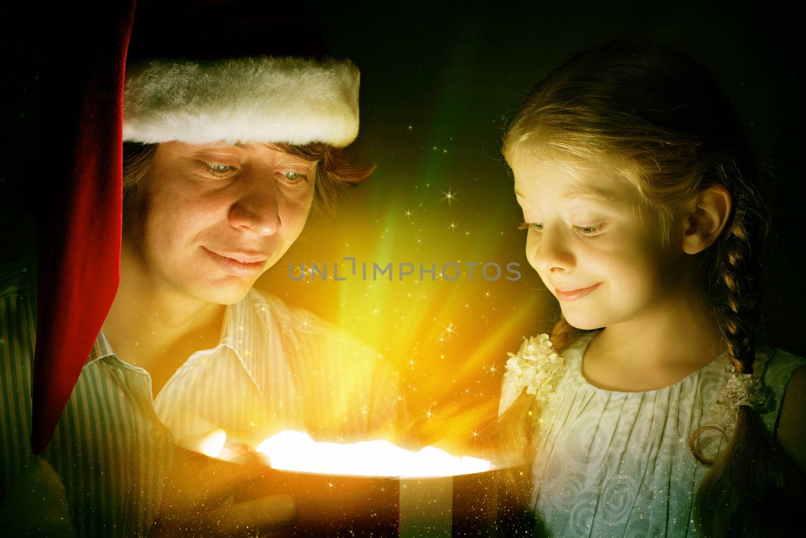 father in Santa Claus cap and daughter opened a box with Christmas gift boxes of shining light and magic