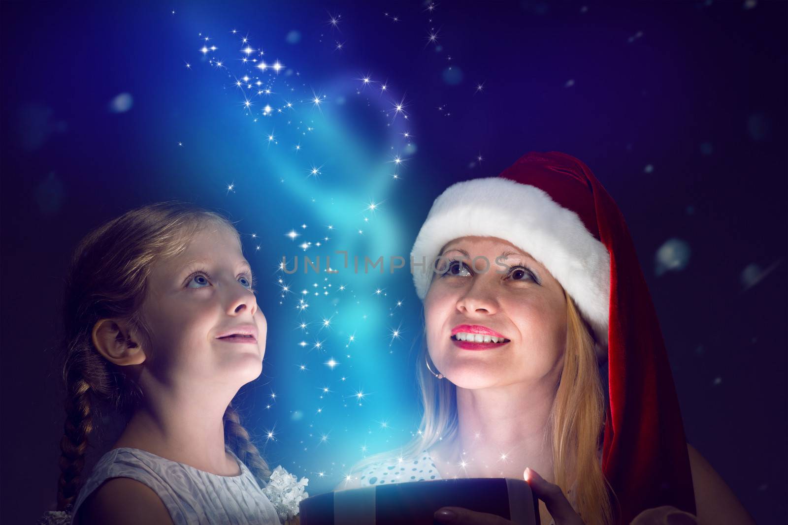 mother in Santa Claus cap and daughter opened a box with Christmas gift boxes of shining light and magic