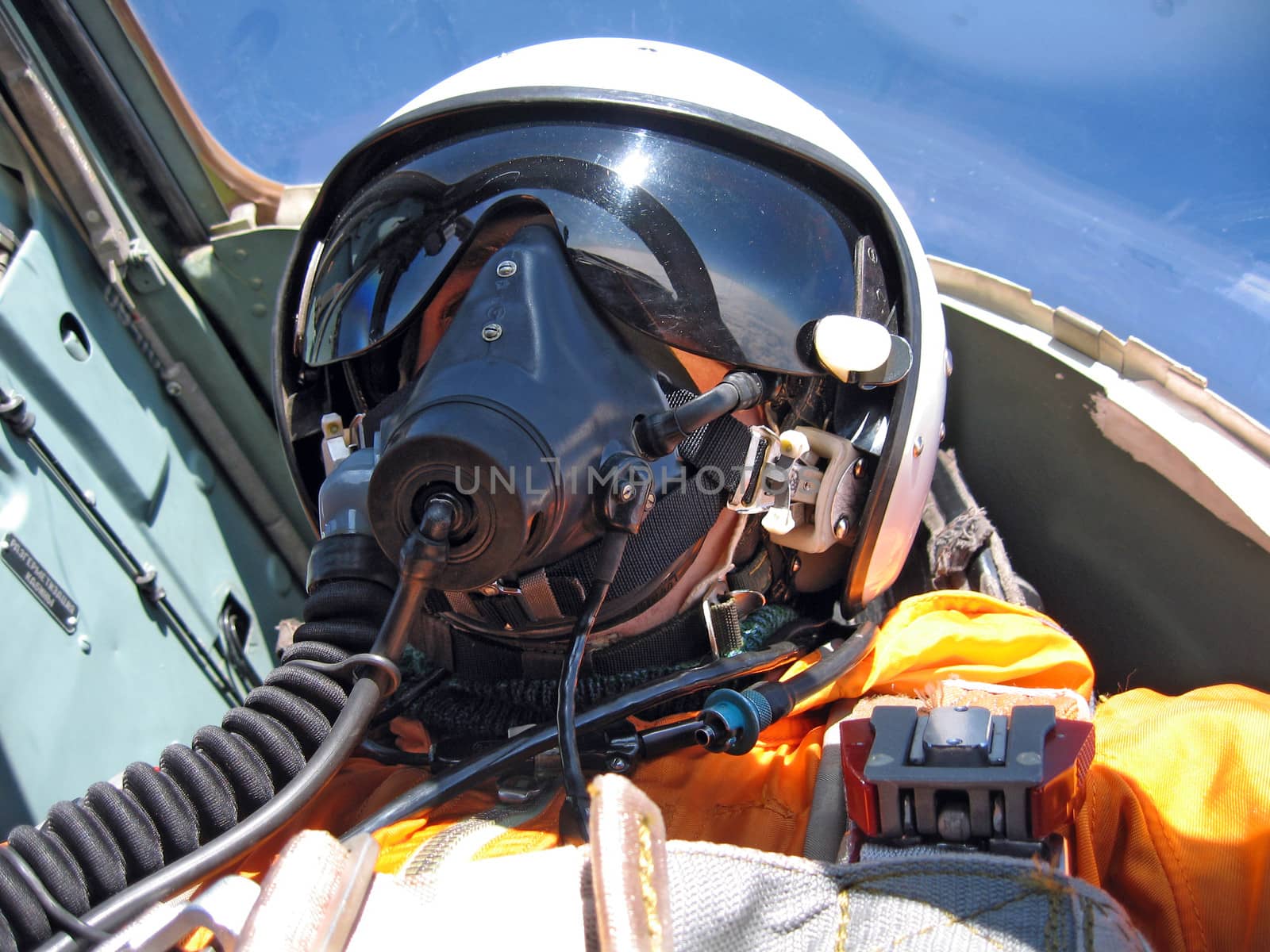 military pilot in the plane in a helmet in dark blue overalls against the blue sky