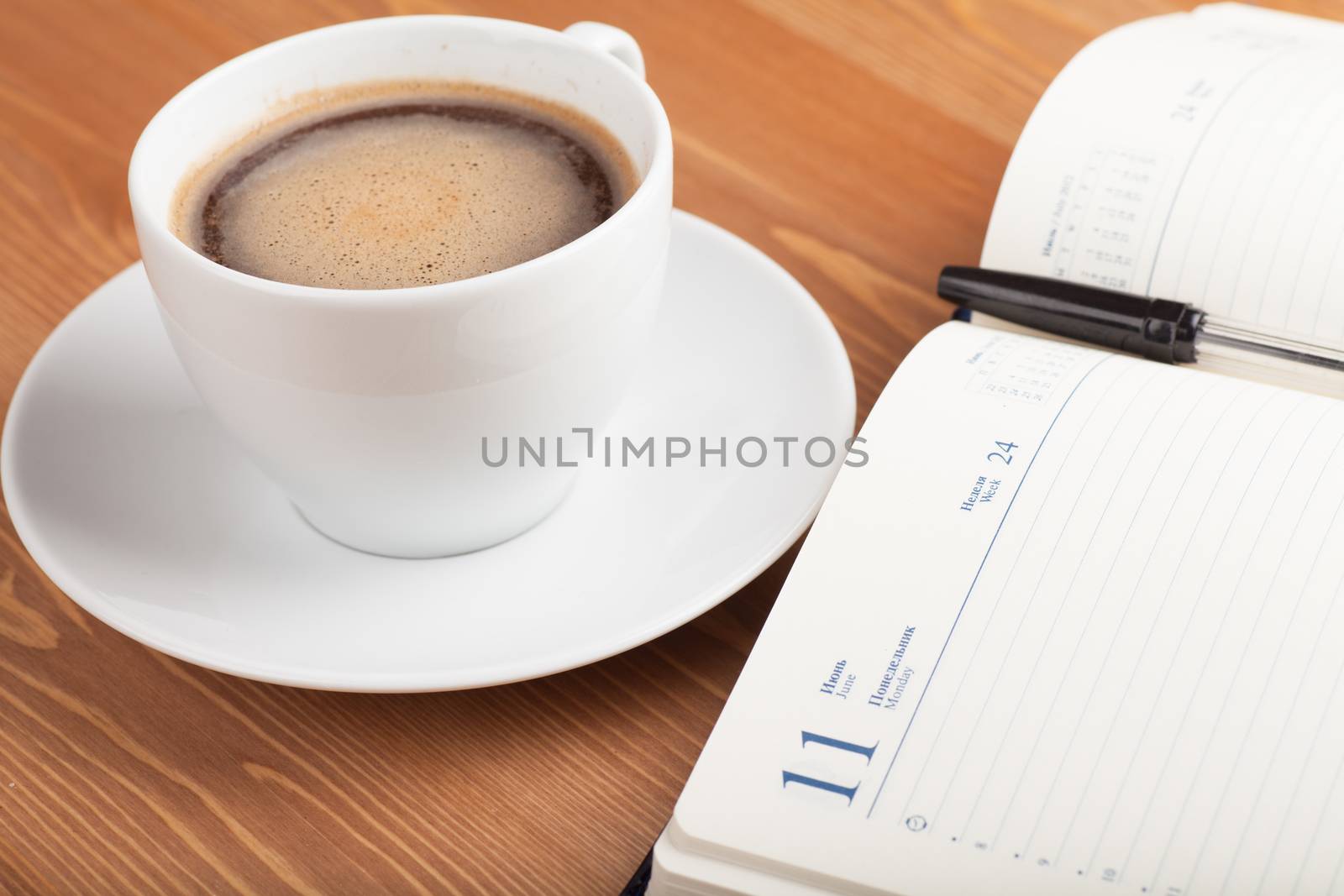 Notebook with pen and cup of coffee on a table. Top view