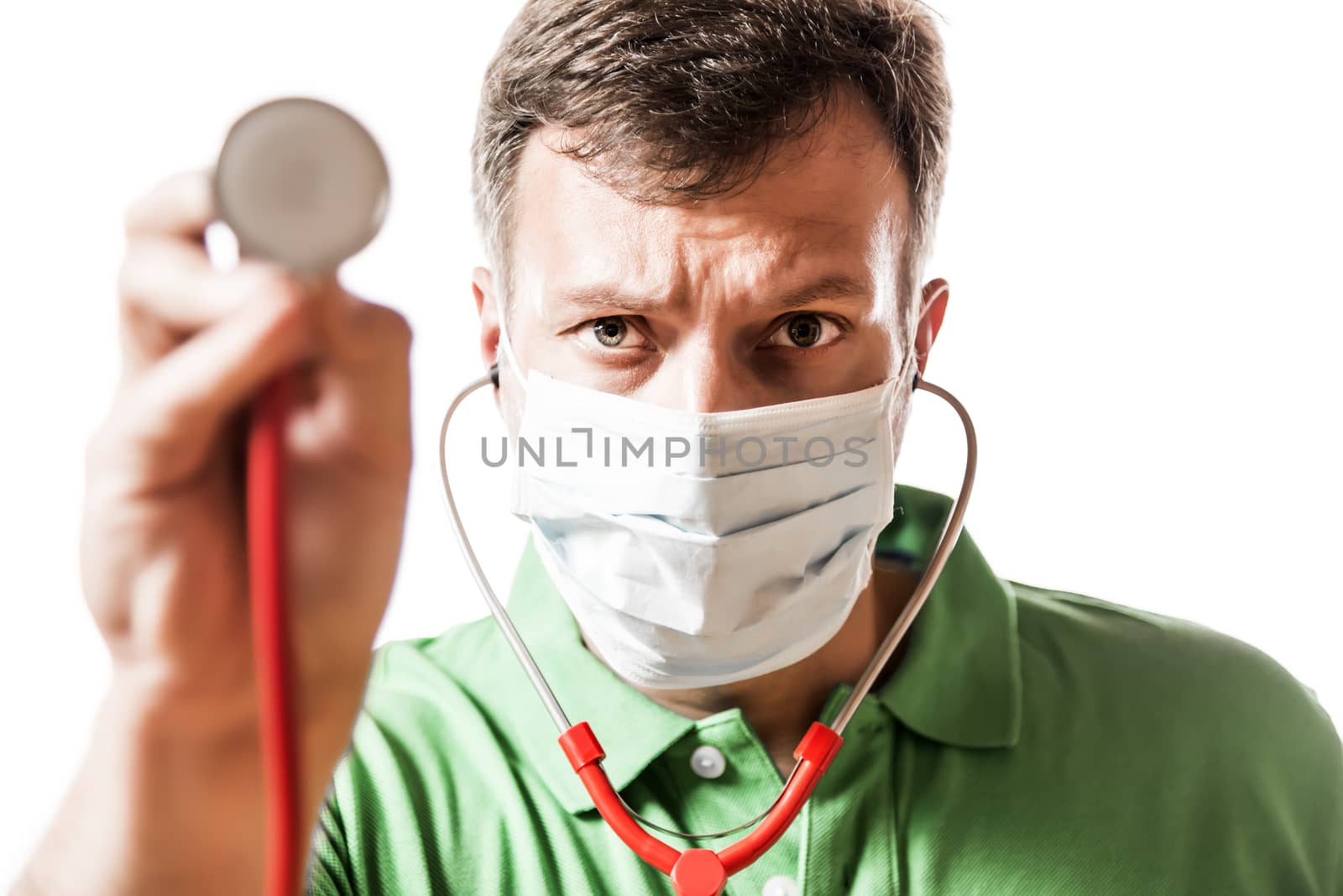 Desperate doctor with surgical mask in green shirt holding his stethoscope