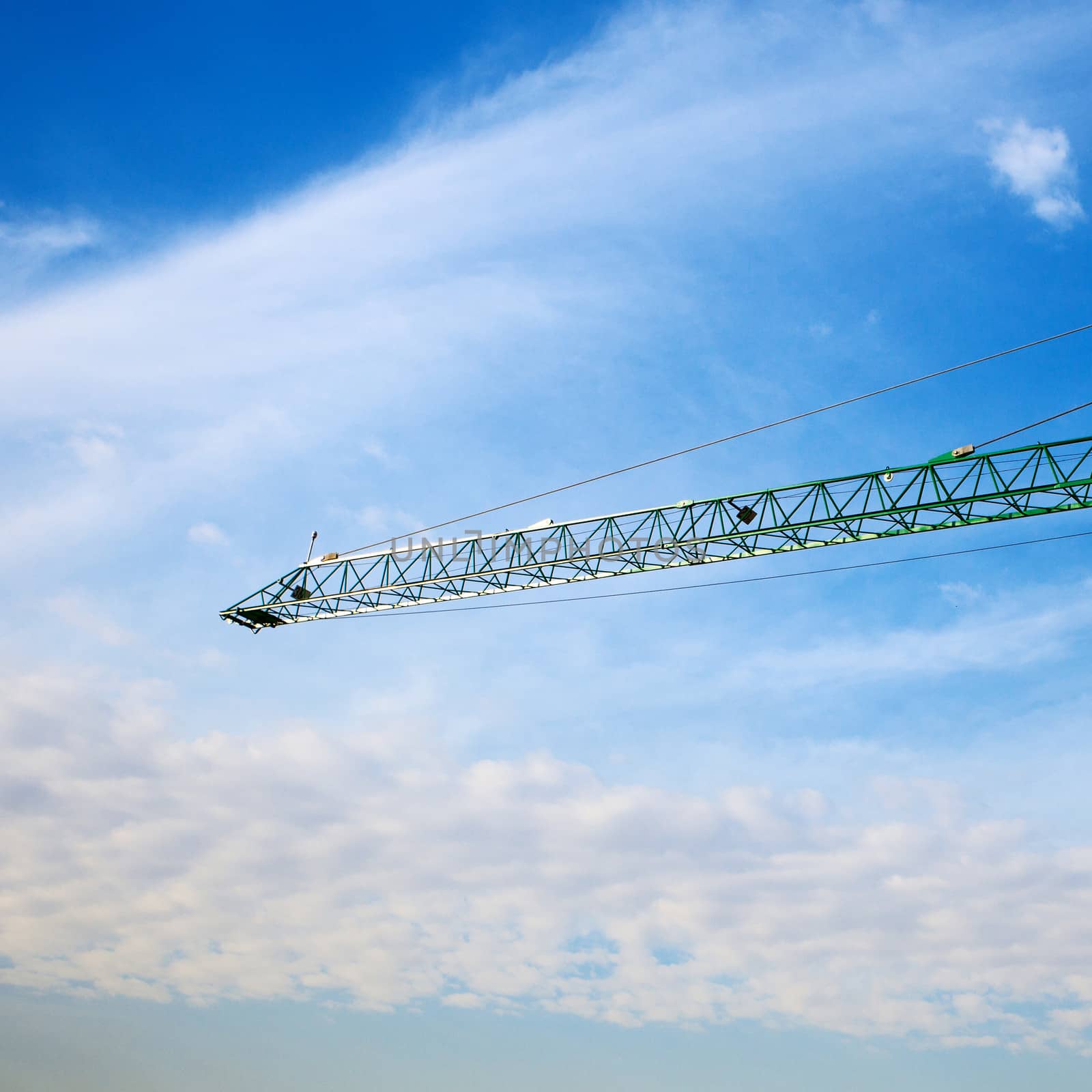 tower crane above the city on a background of blue sky by jannyjus