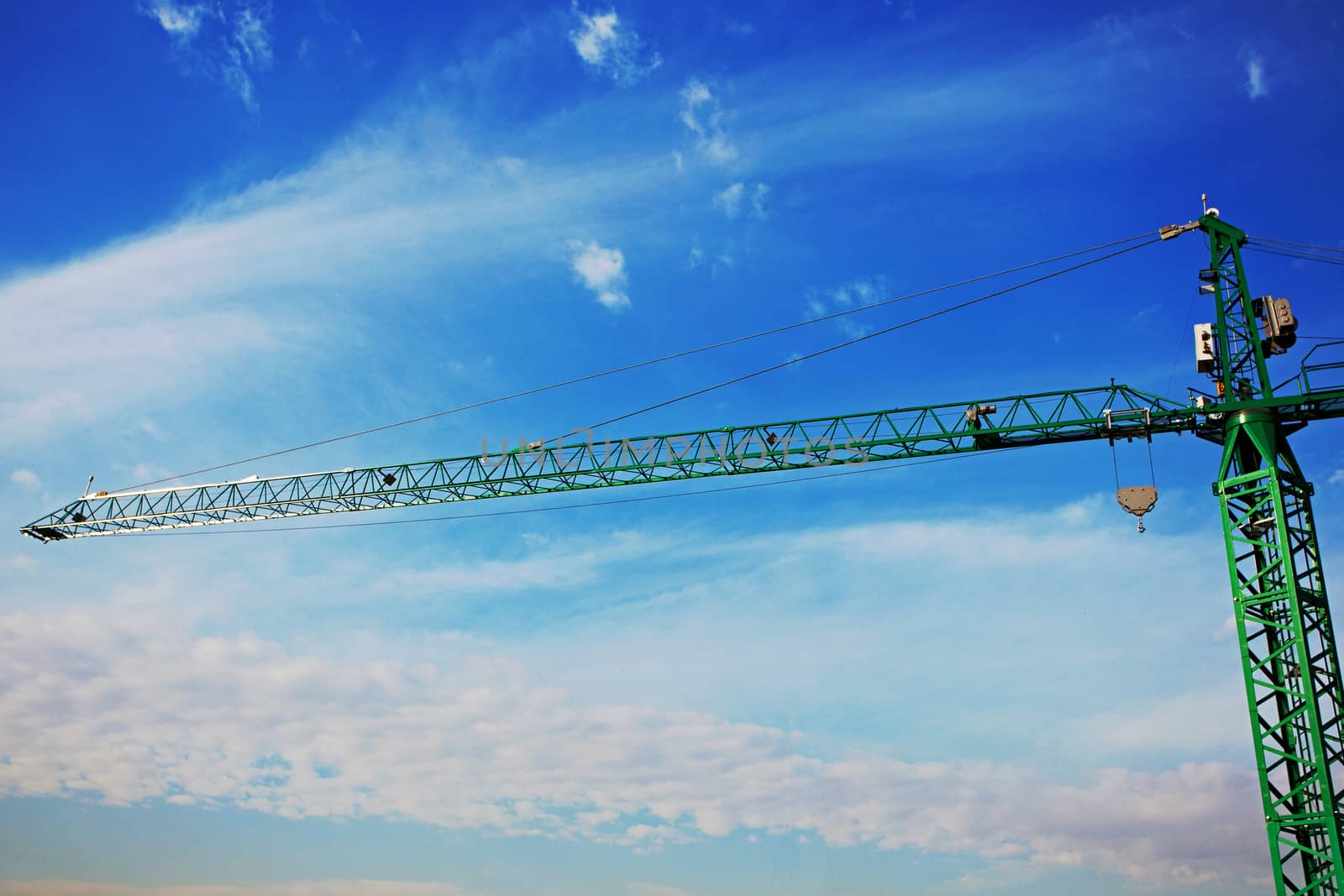 tower crane above the city on a background of blue sky by jannyjus